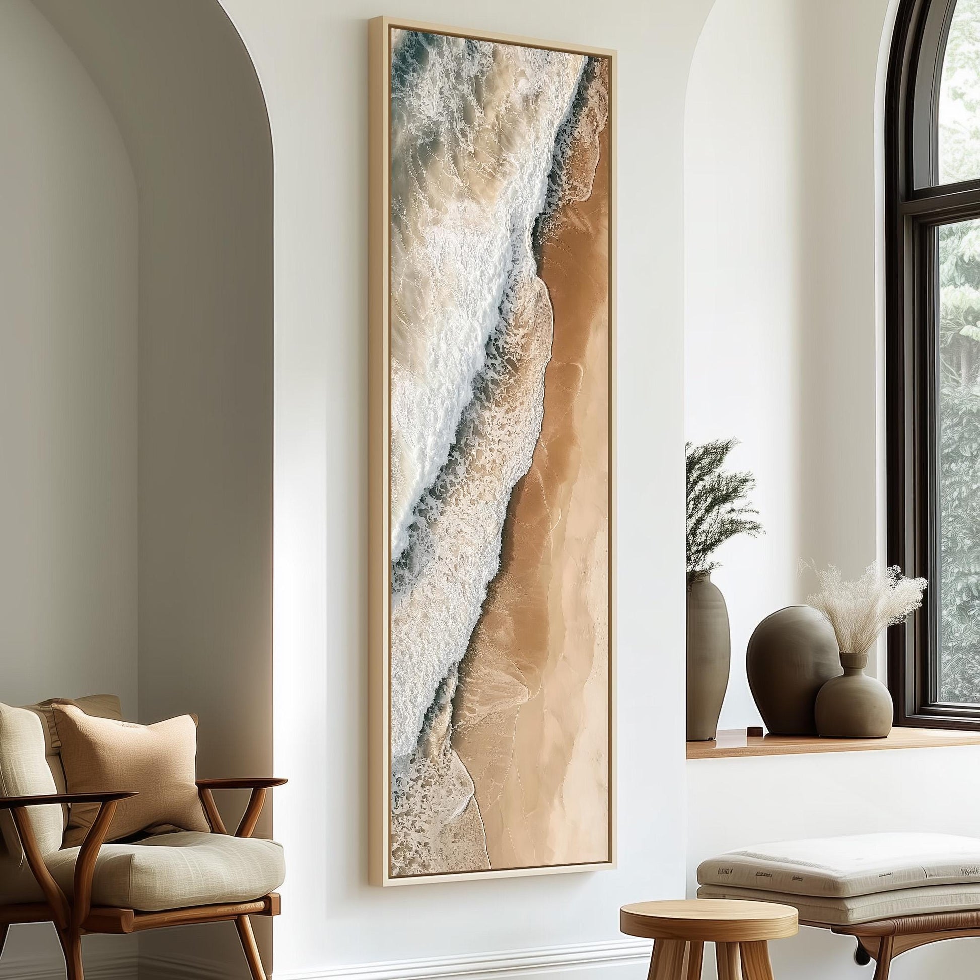 a large framed painting of a beach scene hanging on a wall, with a wooden chair and a small table in the foreground.