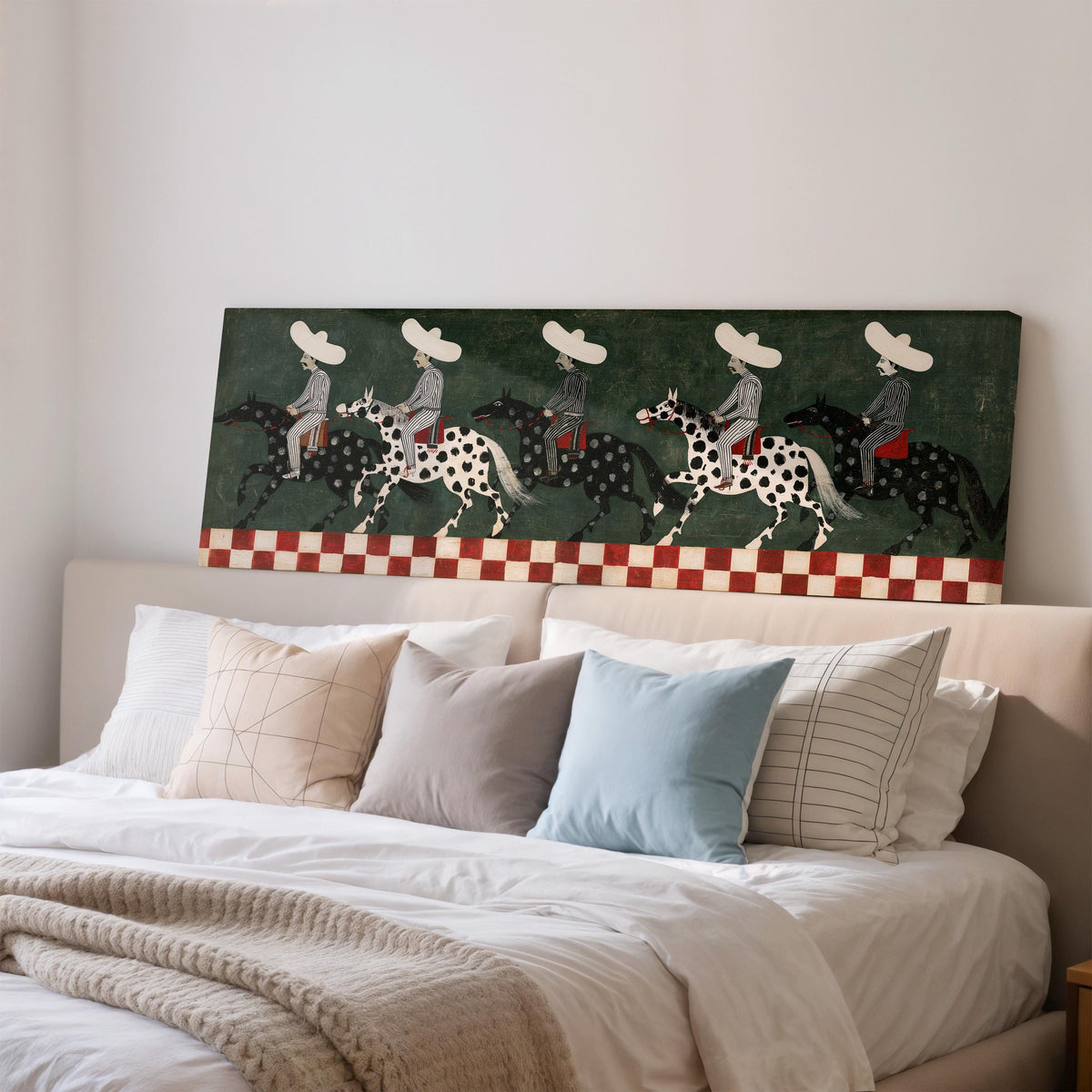 Riders in sombreros on spotted horses wide panoramic canvas print above a bed in a bedroom