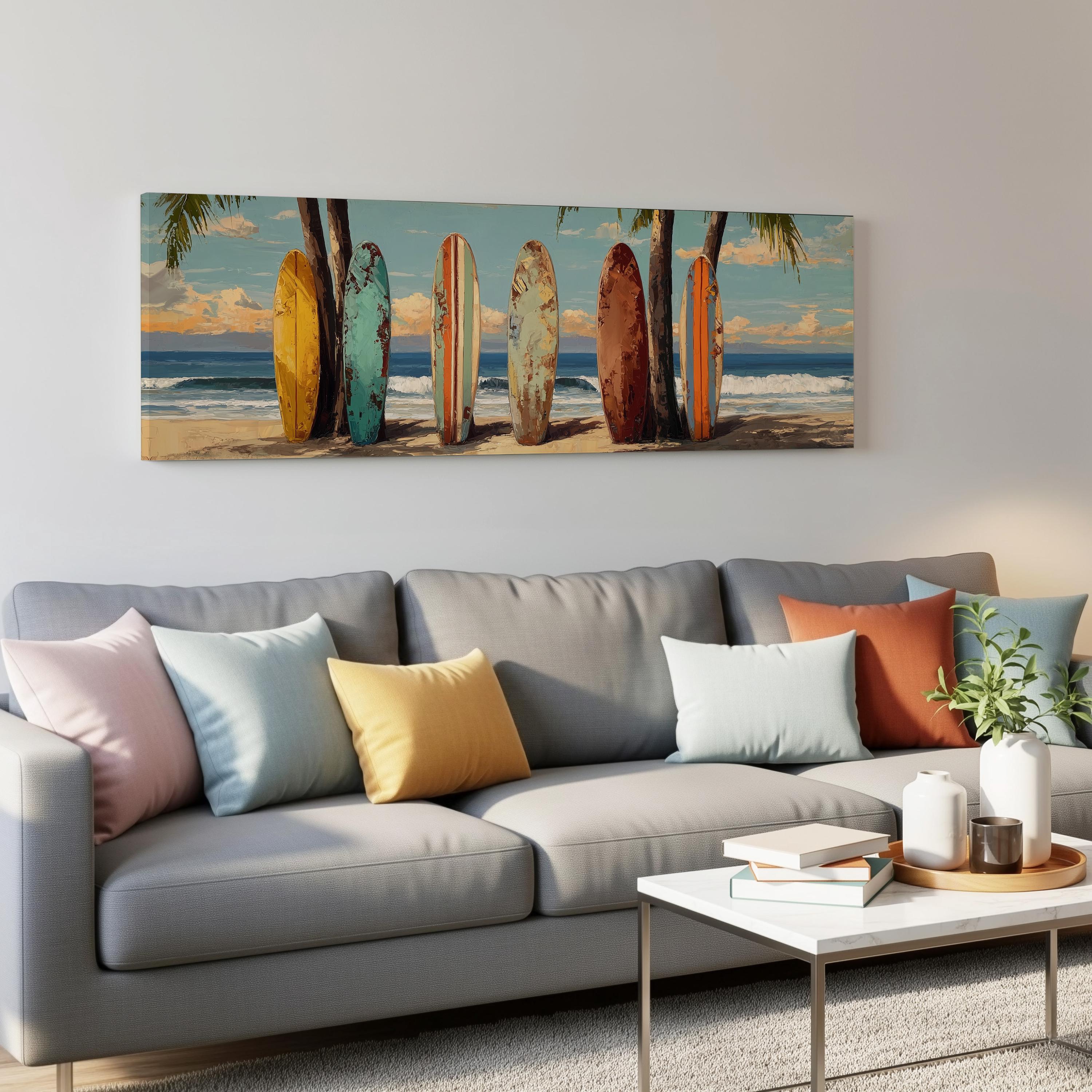 a living room with a gray sofa adorned with colorful throw pillows. Above the sofa, there is a large painting depicting a beach scene with surfboards lined up on the sand.