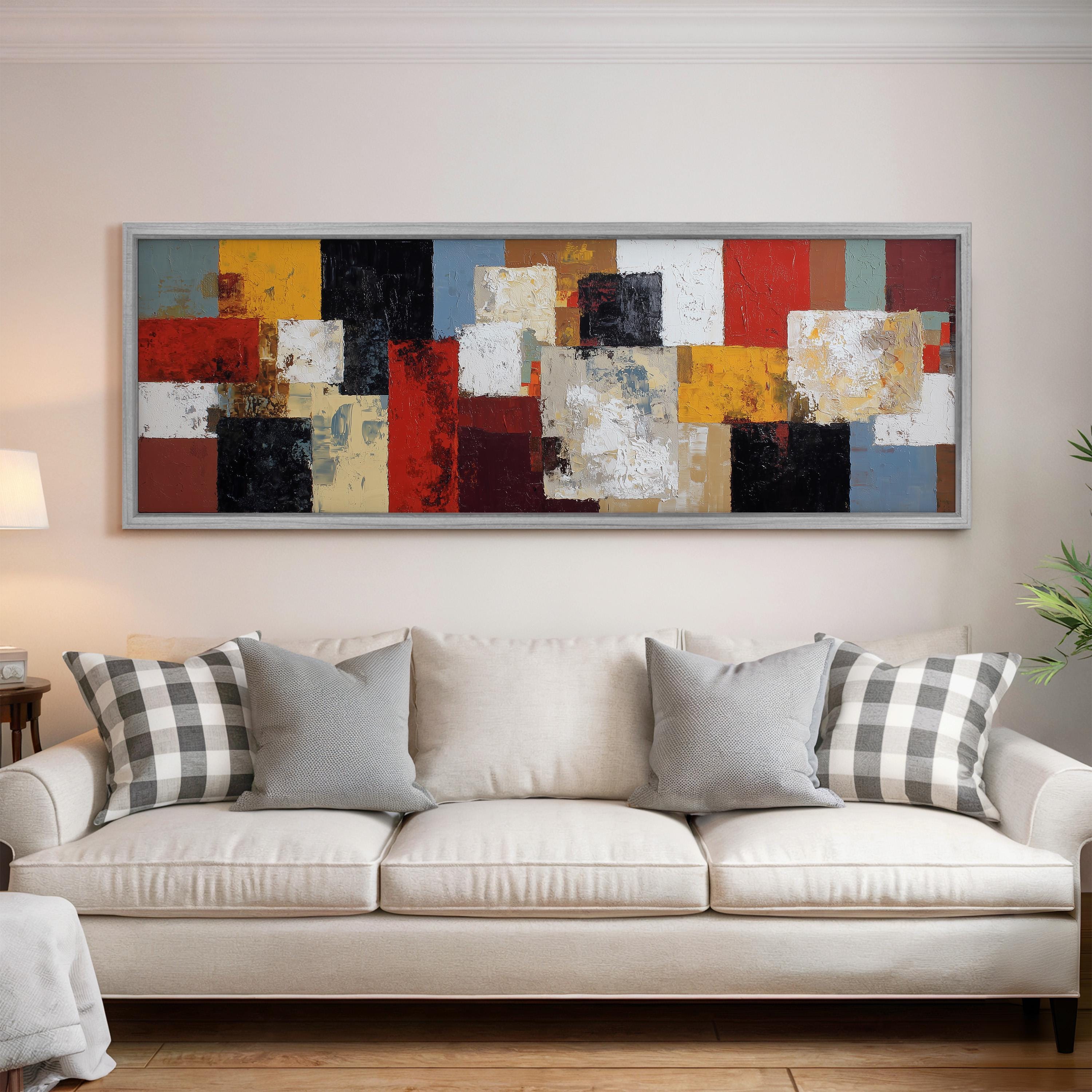 a large, colorful abstract painting hanging on a wall above a white couch with gray and black plaid throw pillows.