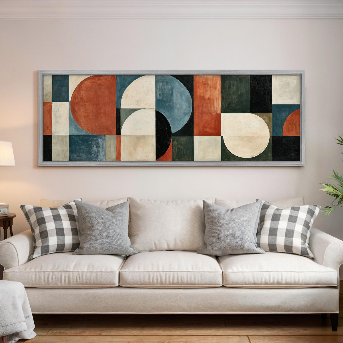 Rust and blue geometric arches and circles panoramic canvas print above a white sofa in a bright living room