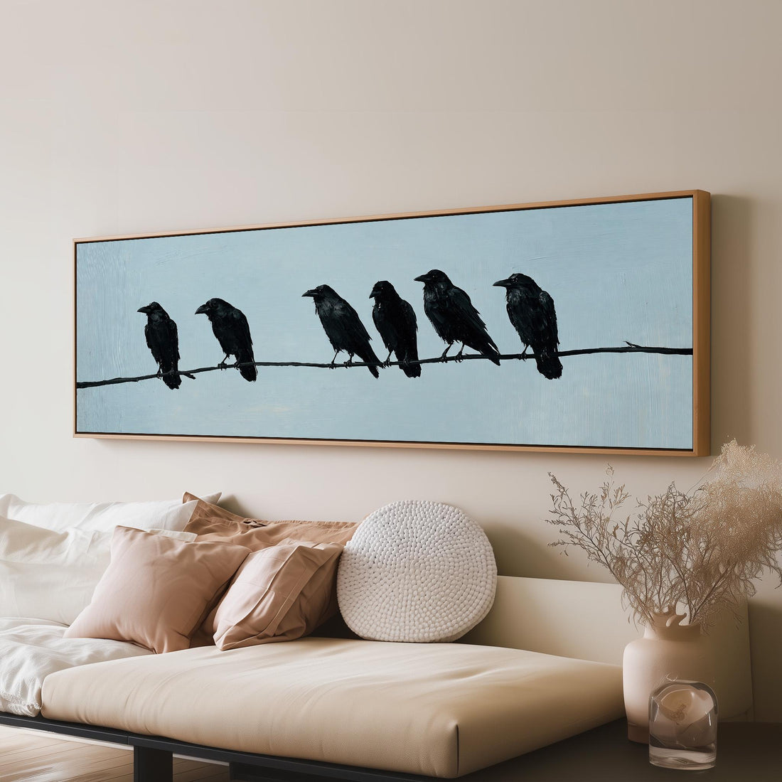 Ravens spaced along a wire long horizontal canvas print above a sofa in a living room