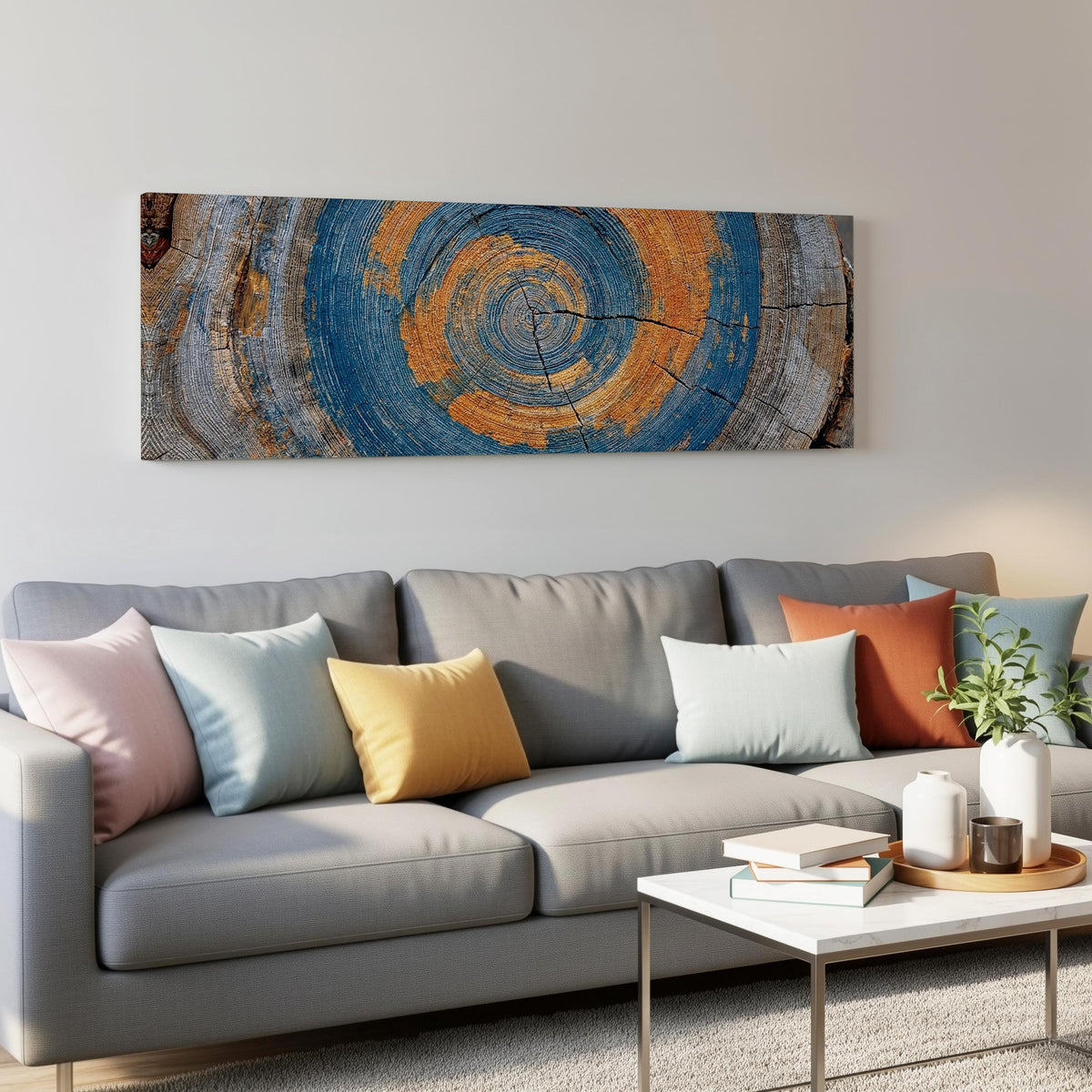 Blue and orange tree ring panoramic canvas print above a grey sofa in a living room