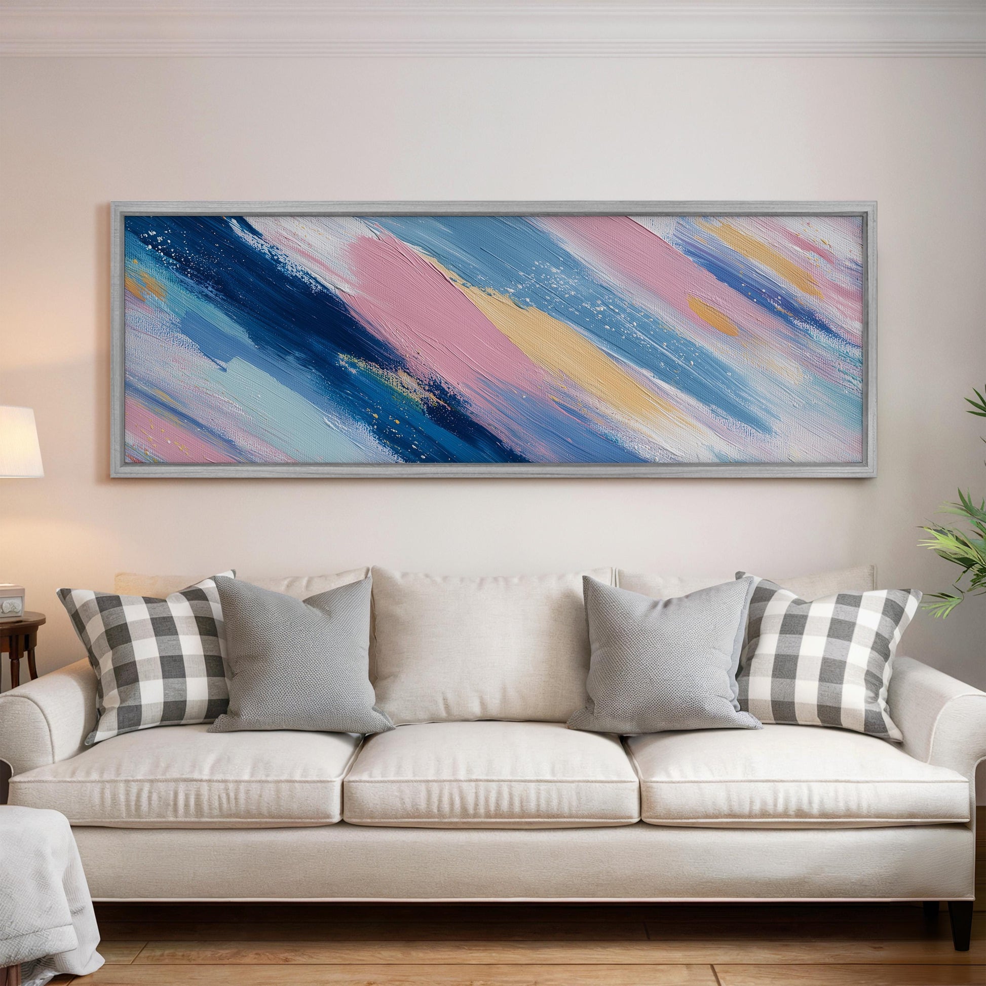 a large, colorful abstract painting hanging on a wall above a white couch with gray and white plaid throw pillows.
