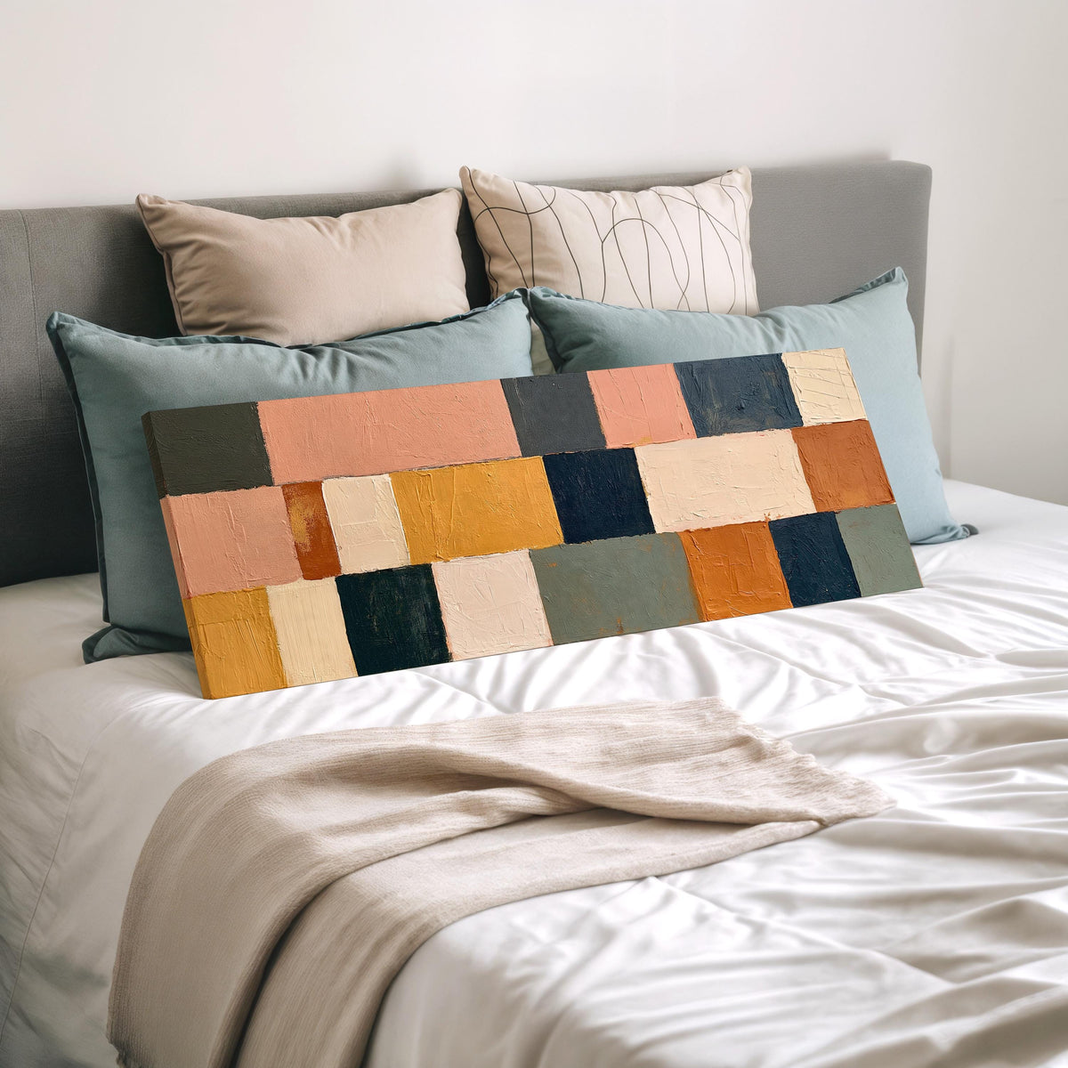Mustard, sage, blush and navy patchwork wide panoramic canvas print laid on a bed to show its size