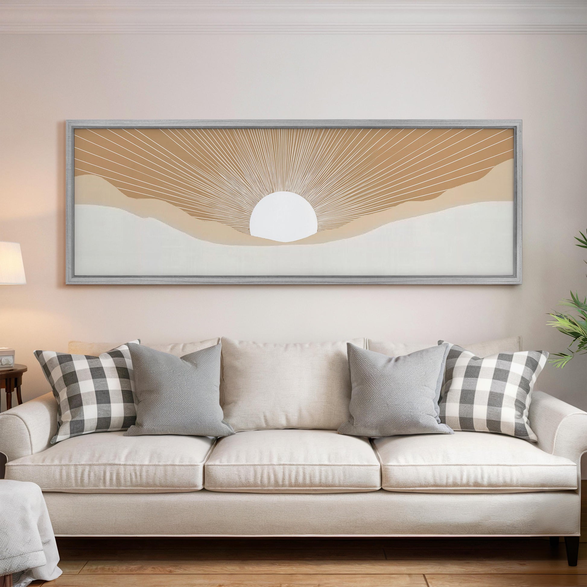 a living room with a white sofa adorned with gray and white plaid throw pillows. Above the sofa, there is a large framed artwork depicting a sun-like design with a white center and rays radiating outwards.