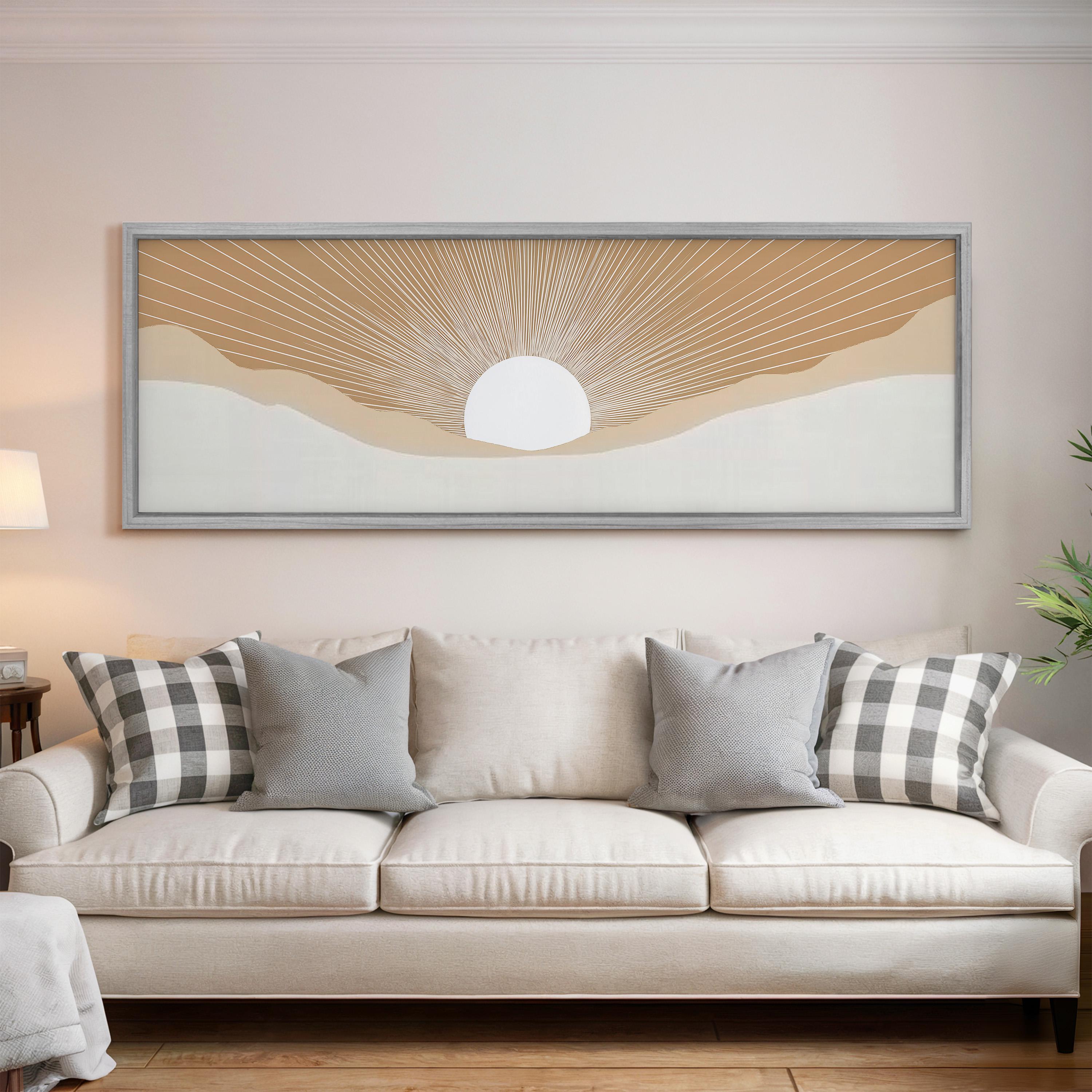 a living room with a white sofa adorned with gray and white plaid throw pillows. Above the sofa, there is a large framed artwork depicting a sun-like design with a white center and rays radiating outwards.