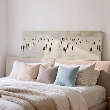 a large painting of people on a snowy landscape hanging above a bed with white bedding and pillows.