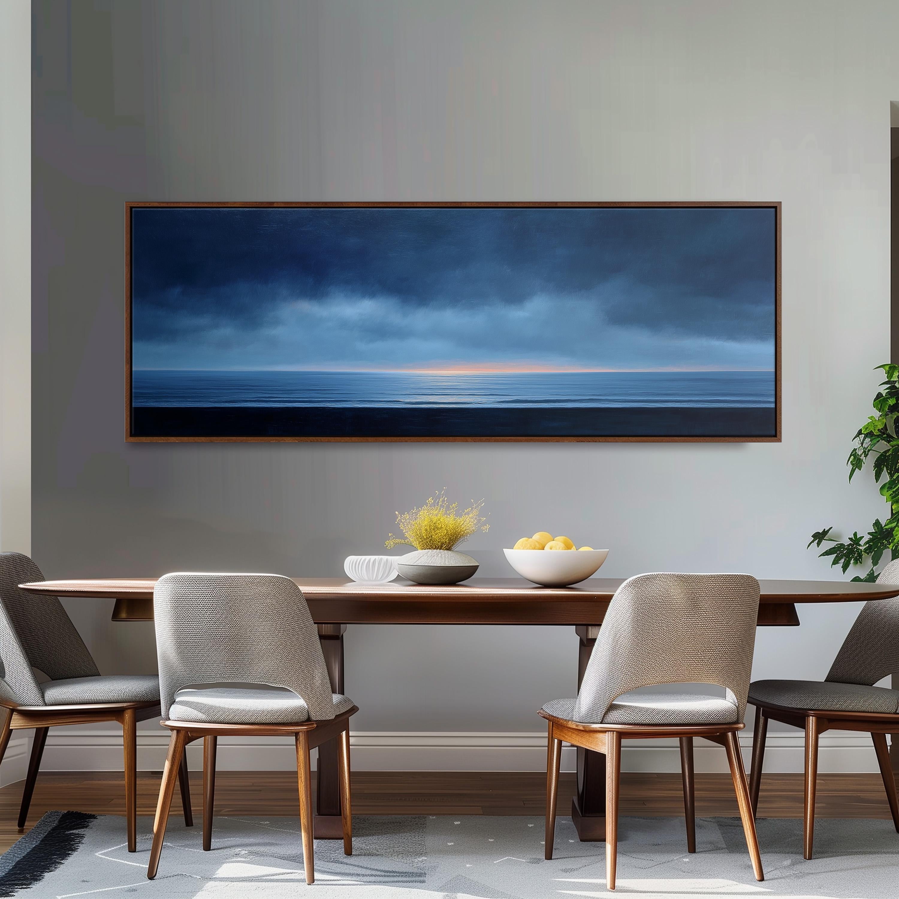 a dining room with a large painting of a serene ocean landscape hanging on the wall above a wooden dining table with four chairs. The table is set with a bowl of fruit and a vase of flowers, creating a cozy and inviting atmosphere.