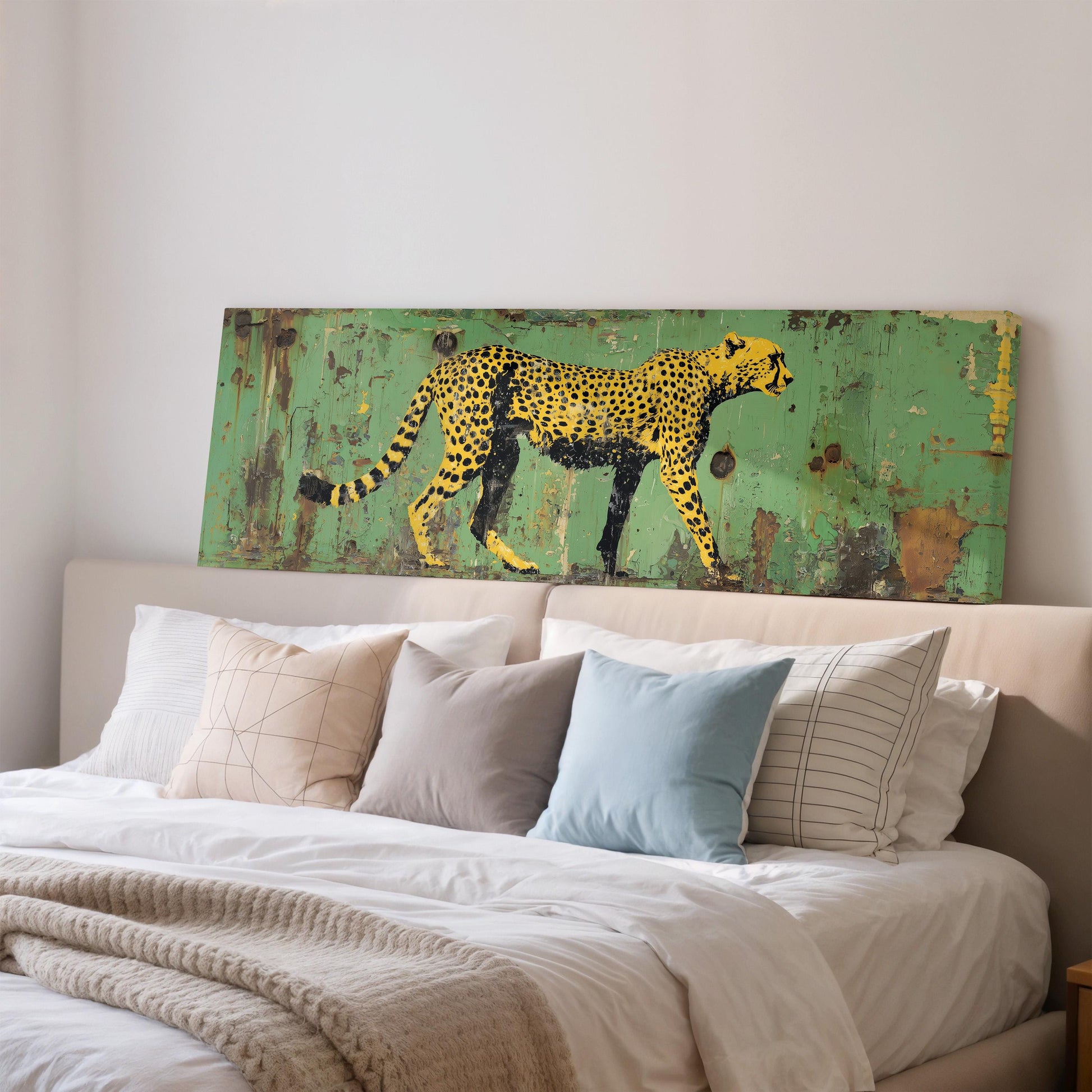 a large painting of a cheetah on a green background, mounted on a wall above a bed with white pillows and a gray blanket.