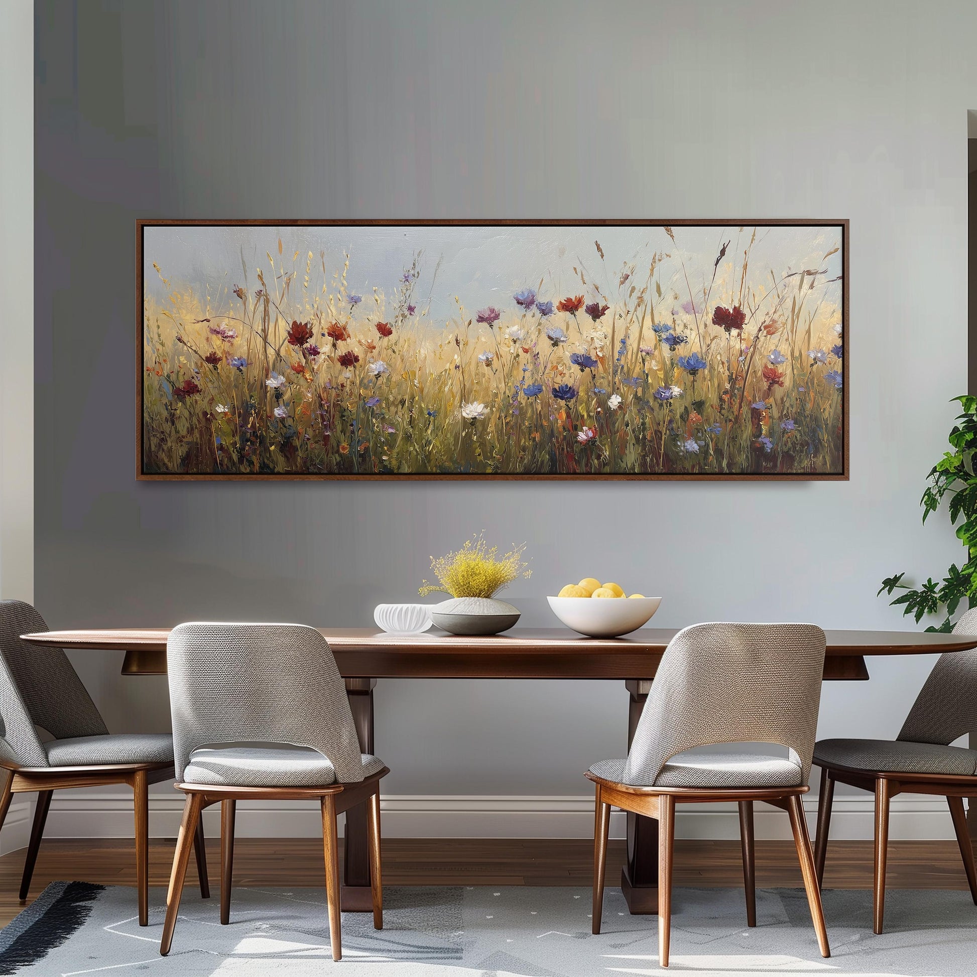 a dining room with a large painting of a field of flowers hanging on the wall above a wooden dining table with four chairs. The table is set with a bowl of fruit and a vase of flowers, creating a cozy and inviting atmosphere.