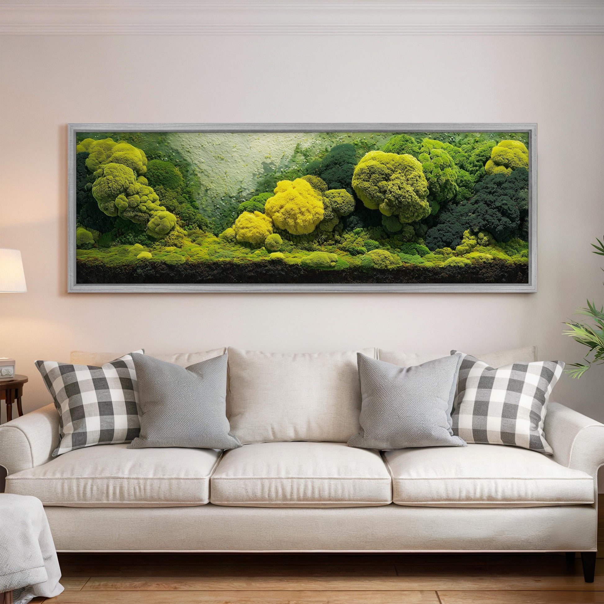 a large, framed painting of a lush, verdant landscape with a variety of trees and foliage, hanging on a wall above a white sofa with patterned throw pillows.