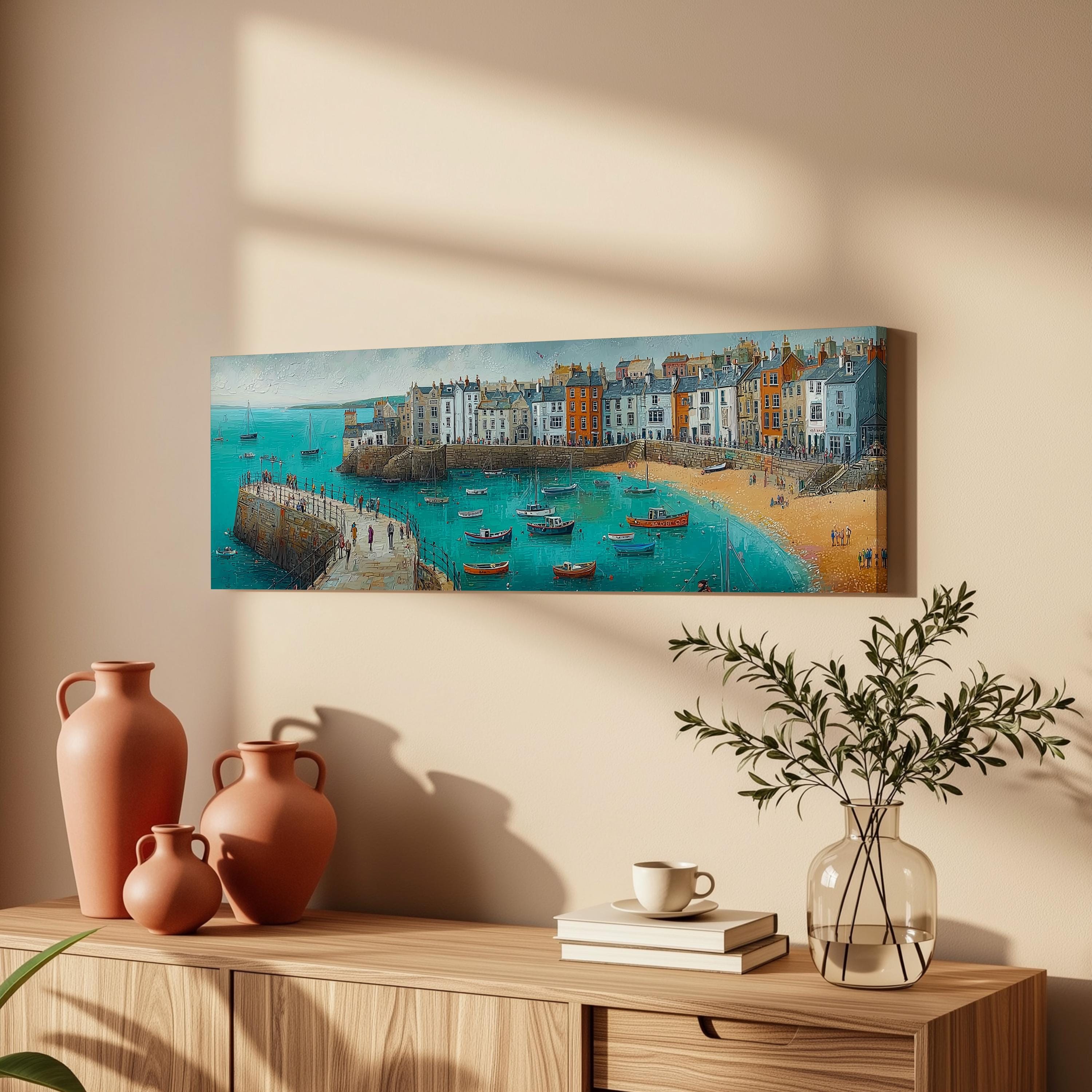 a wooden cabinet with a painting of a coastal town hanging on the wall above it. The painting depicts a picturesque scene of a small town nestled by the sea, with boats dotting the tranquil waters. The cabinet also holds a vase, a stack of books, and a potted plant, creating a cozy and inviting atmosphere in the room.