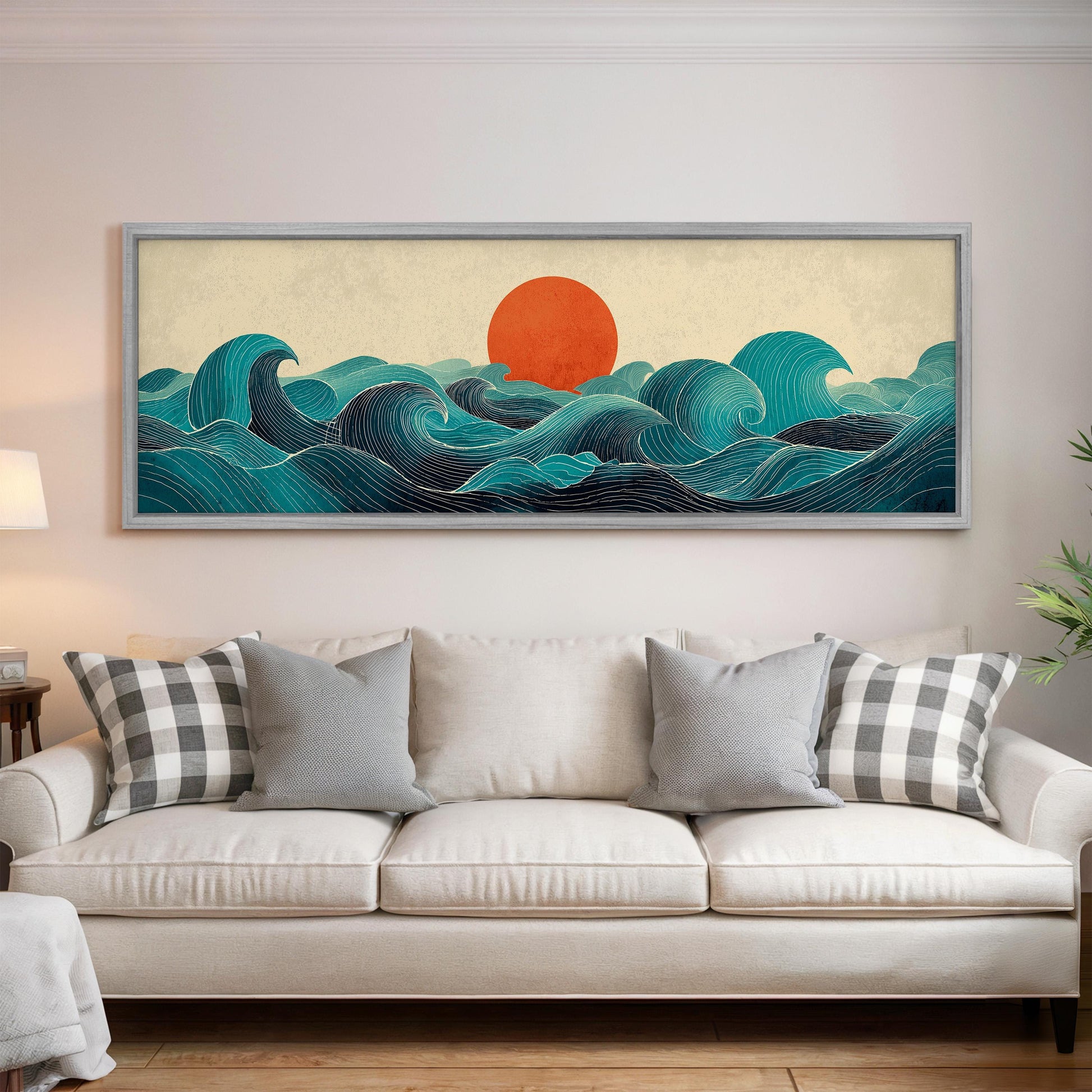 a large, framed artwork depicting a seascape with a sun in the background, hanging on a wall above a white couch with patterned throw pillows.
