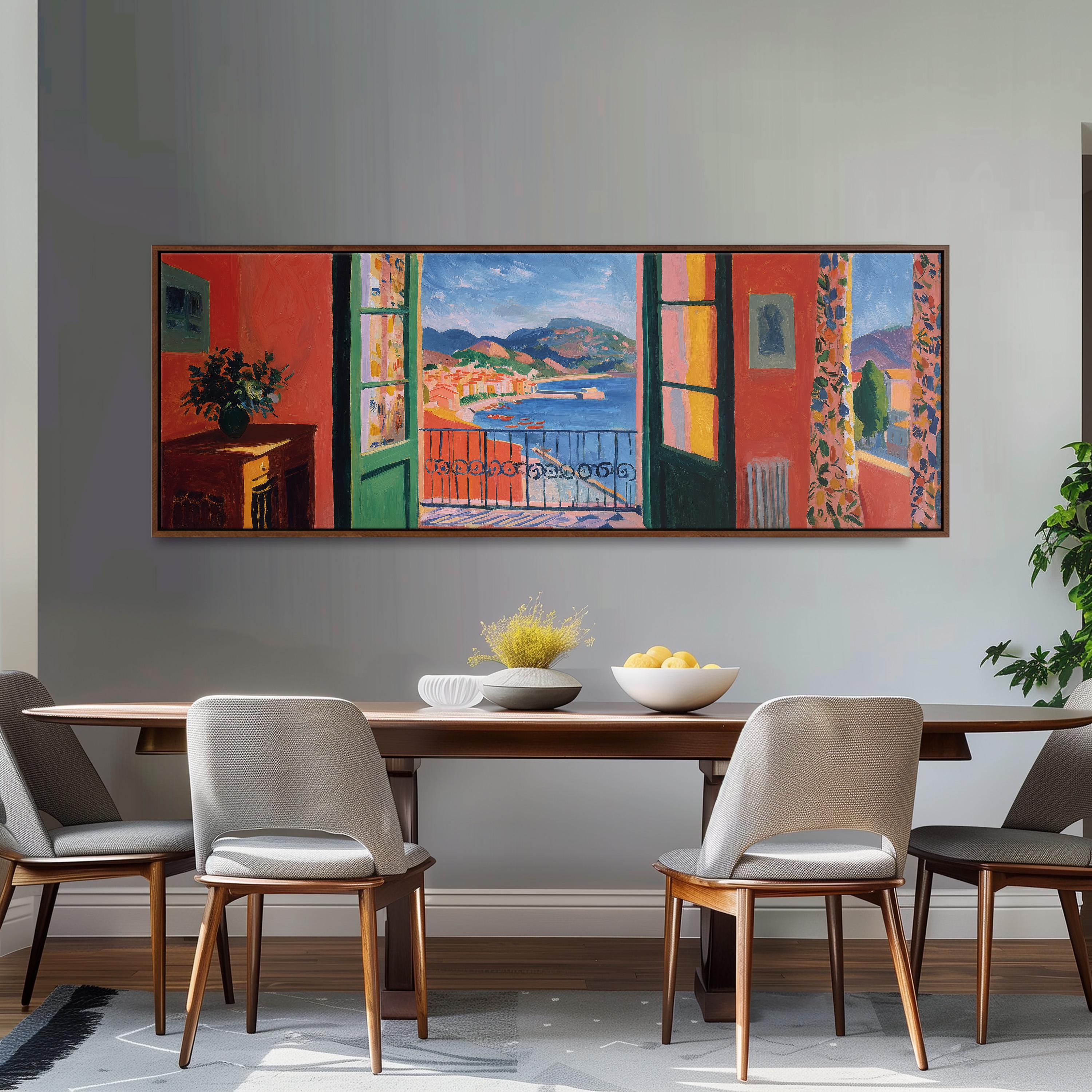 a dining room with a large, colorful painting of a balcony overlooking a scenic view of a town and a body of water. The painting is hung on the wall above a wooden dining table with four chairs. The table is set with a bowl of fruit and a vase of flowers, creating a welcoming and inviting atmosphere.