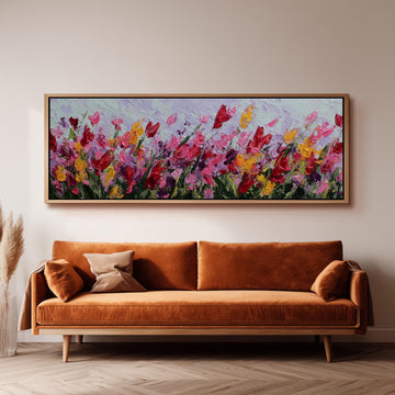 a large, vibrant painting of flowers hanging on a wall above a brown sofa.