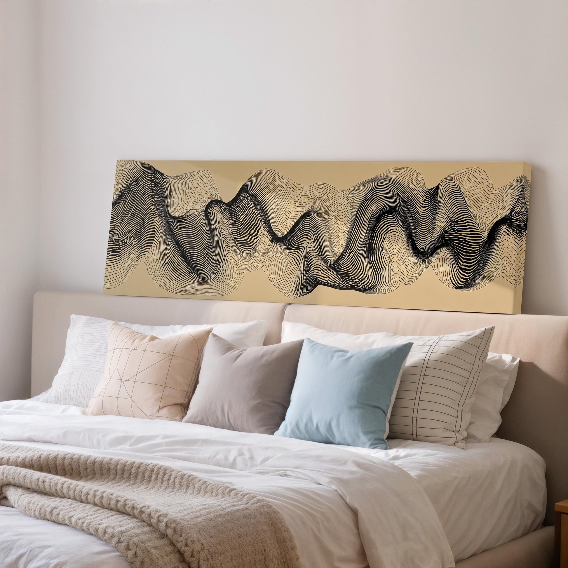 a large bed with a white comforter and various pillows, including a blue pillow and a striped pillow. Above the bed, there is a large abstract painting or artwork with a wave-like pattern in black and white.