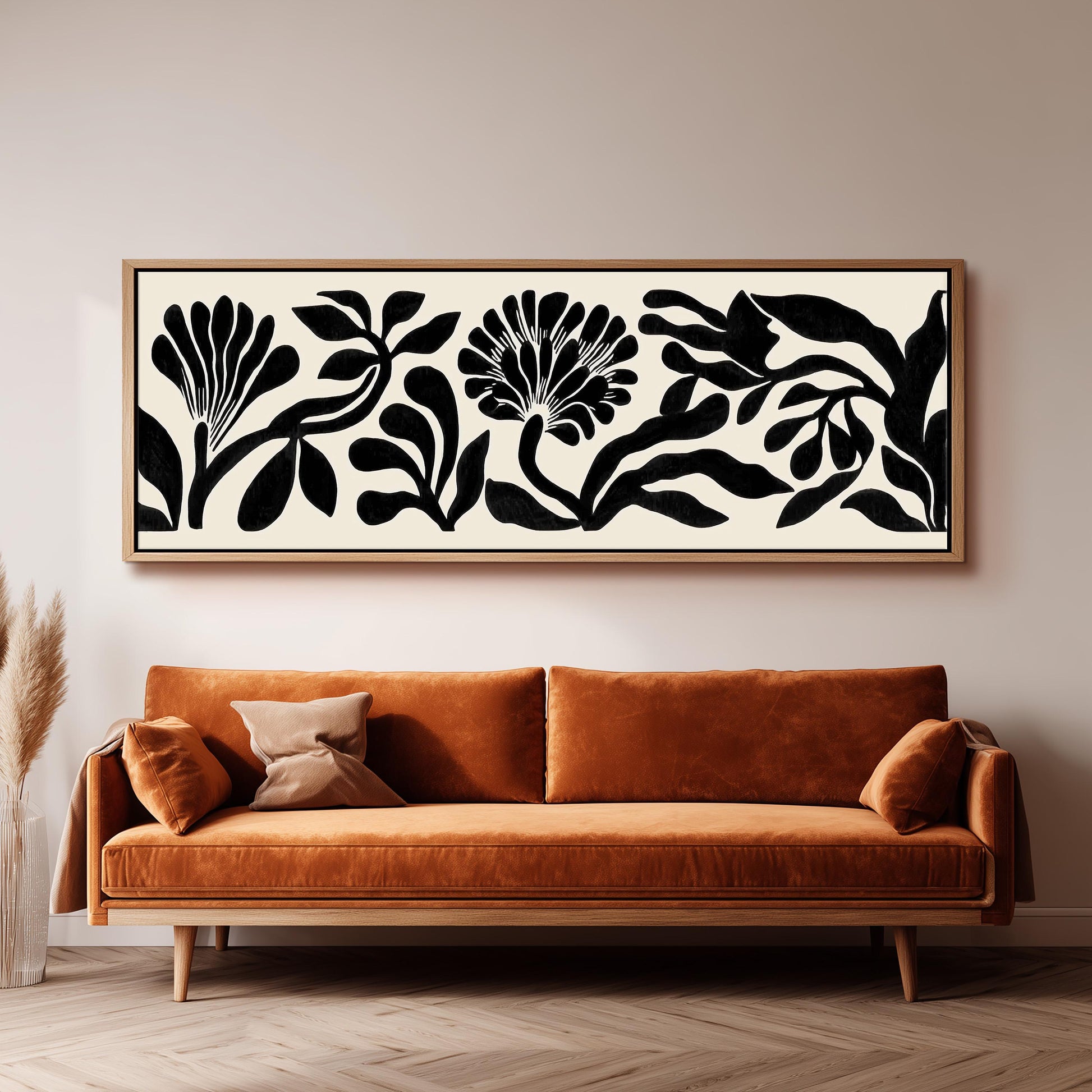 a large black and white abstract floral artwork hanging on a wall above a brown sofa.