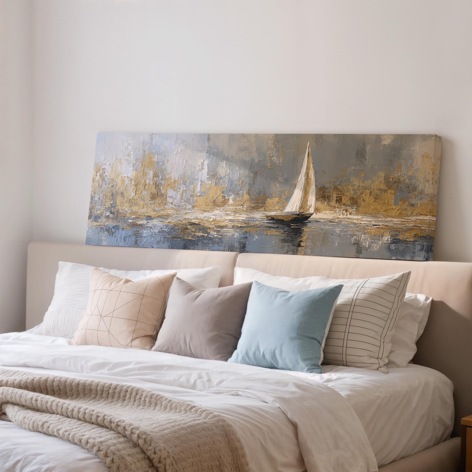 a large painting of a sailboat on a body of water, hanging above a bed with white pillows and a gray blanket.