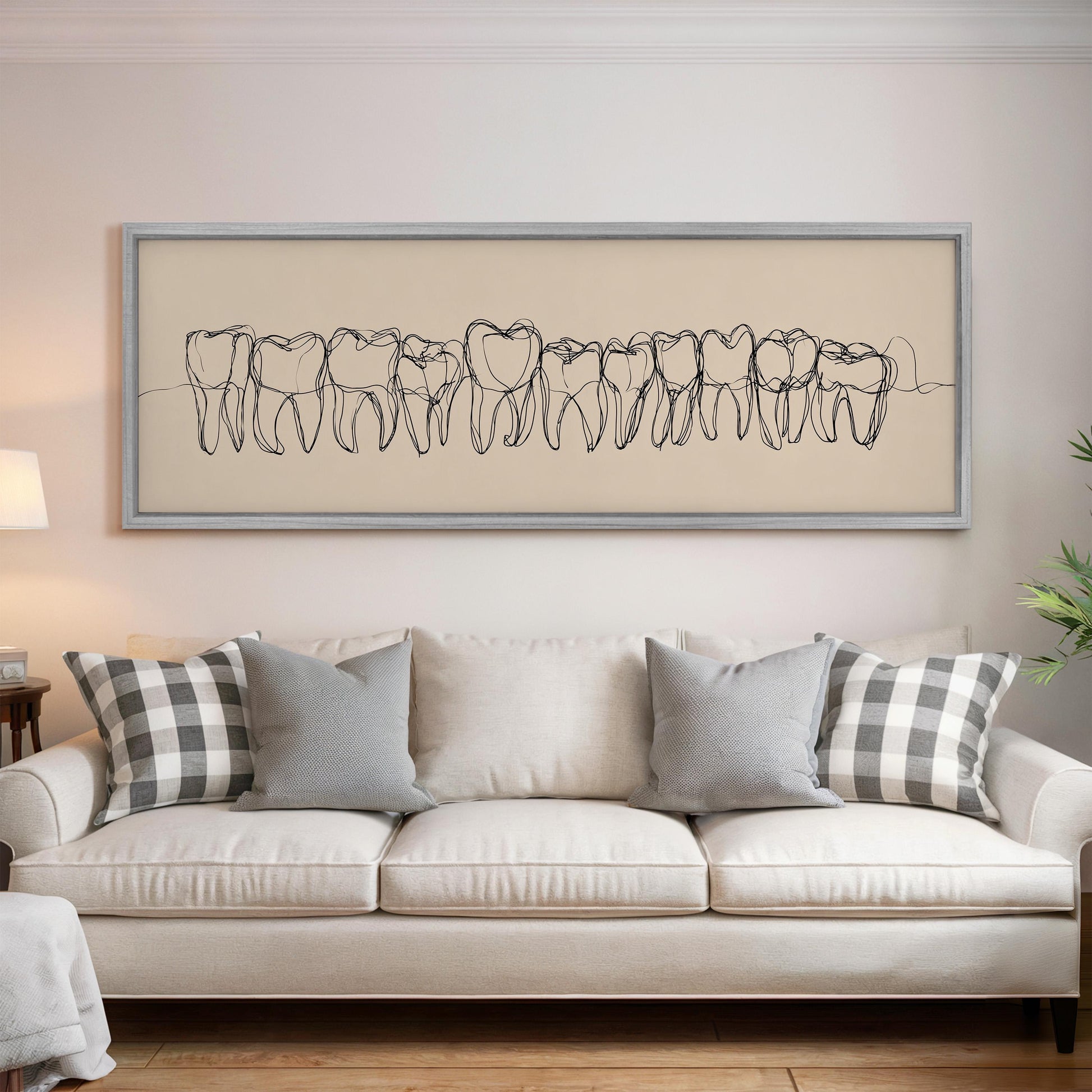 a living room with a white sofa and a framed drawing of teeth on the wall above it.