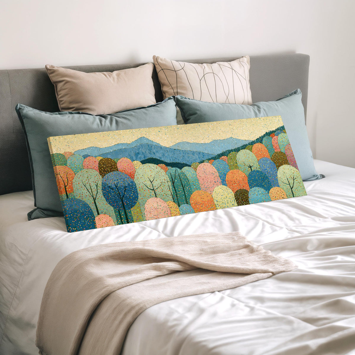Pastel dotted forest below blue mountains wide panoramic canvas print laid on a bed to show its size