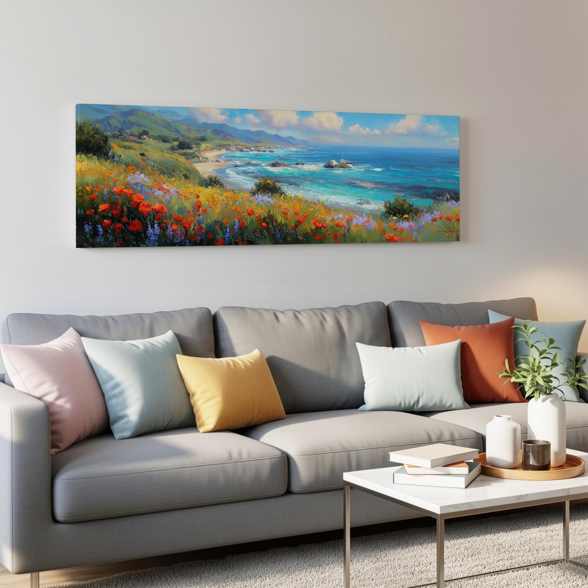 a large, colorful painting of a coastal landscape hanging on a wall above a gray couch with colorful throw pillows.