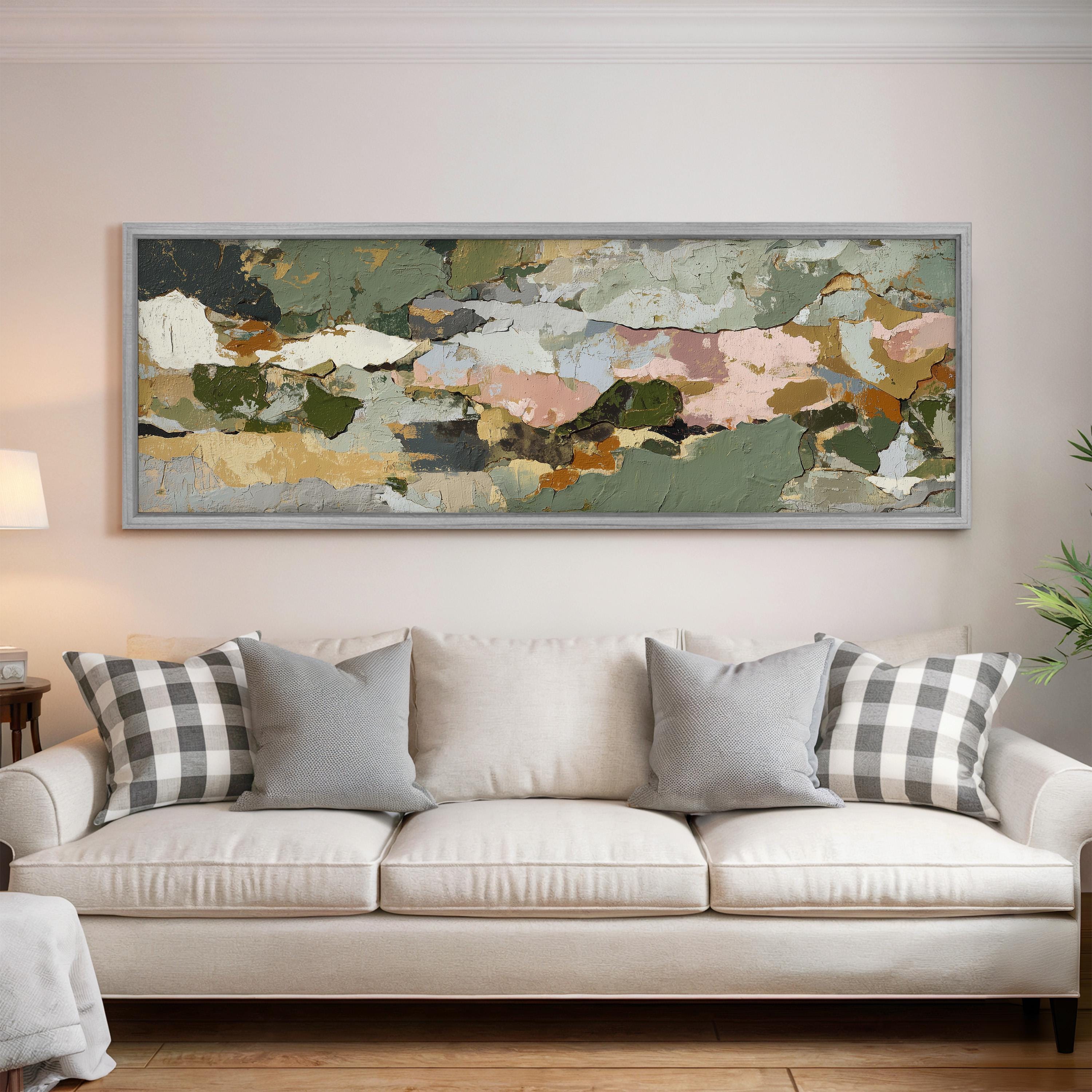 a large, colorful abstract painting hanging on a wall above a white couch with gray and white plaid throw pillows.