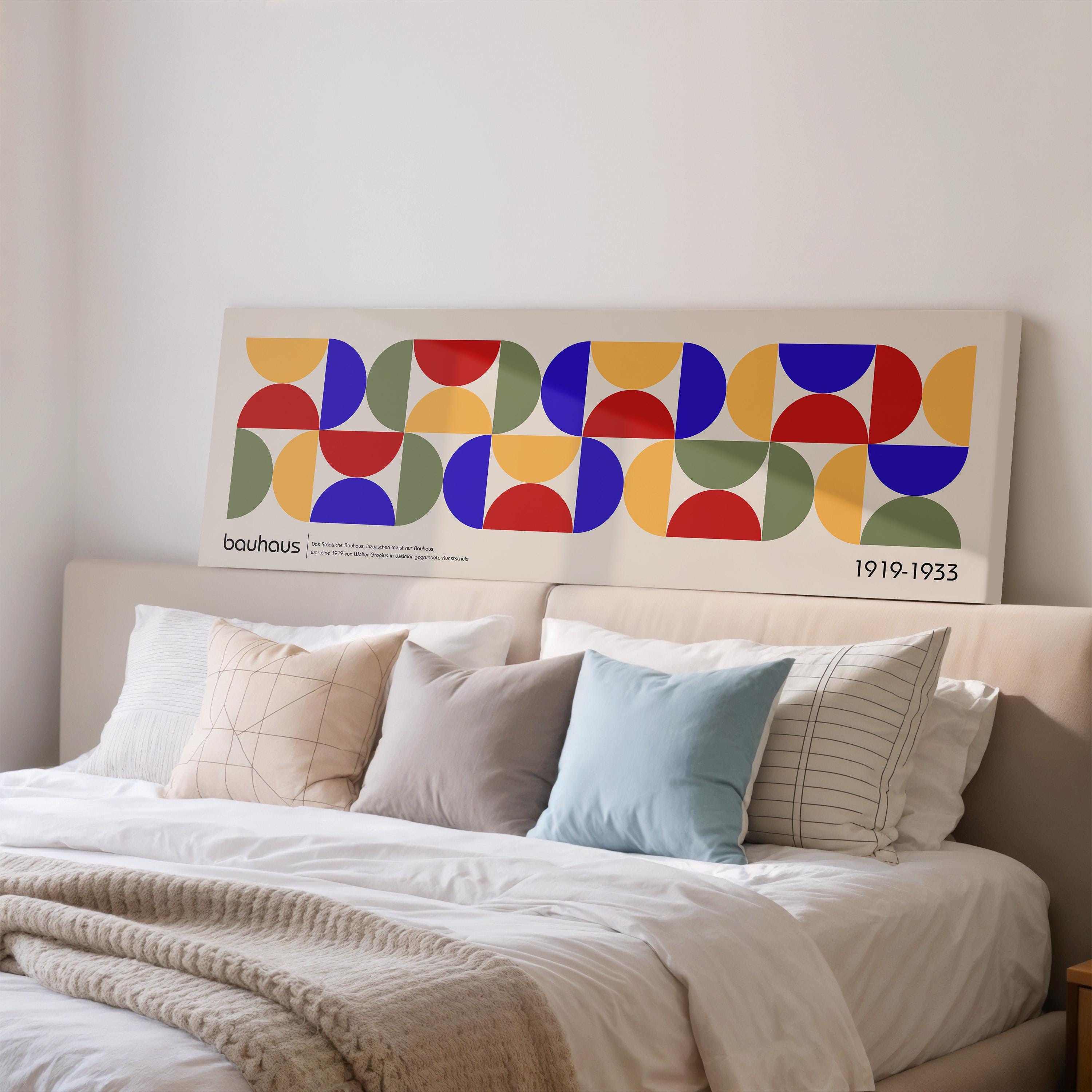 a large abstract painting with a geometric design on a wall above a bed with white bedding and pillows.