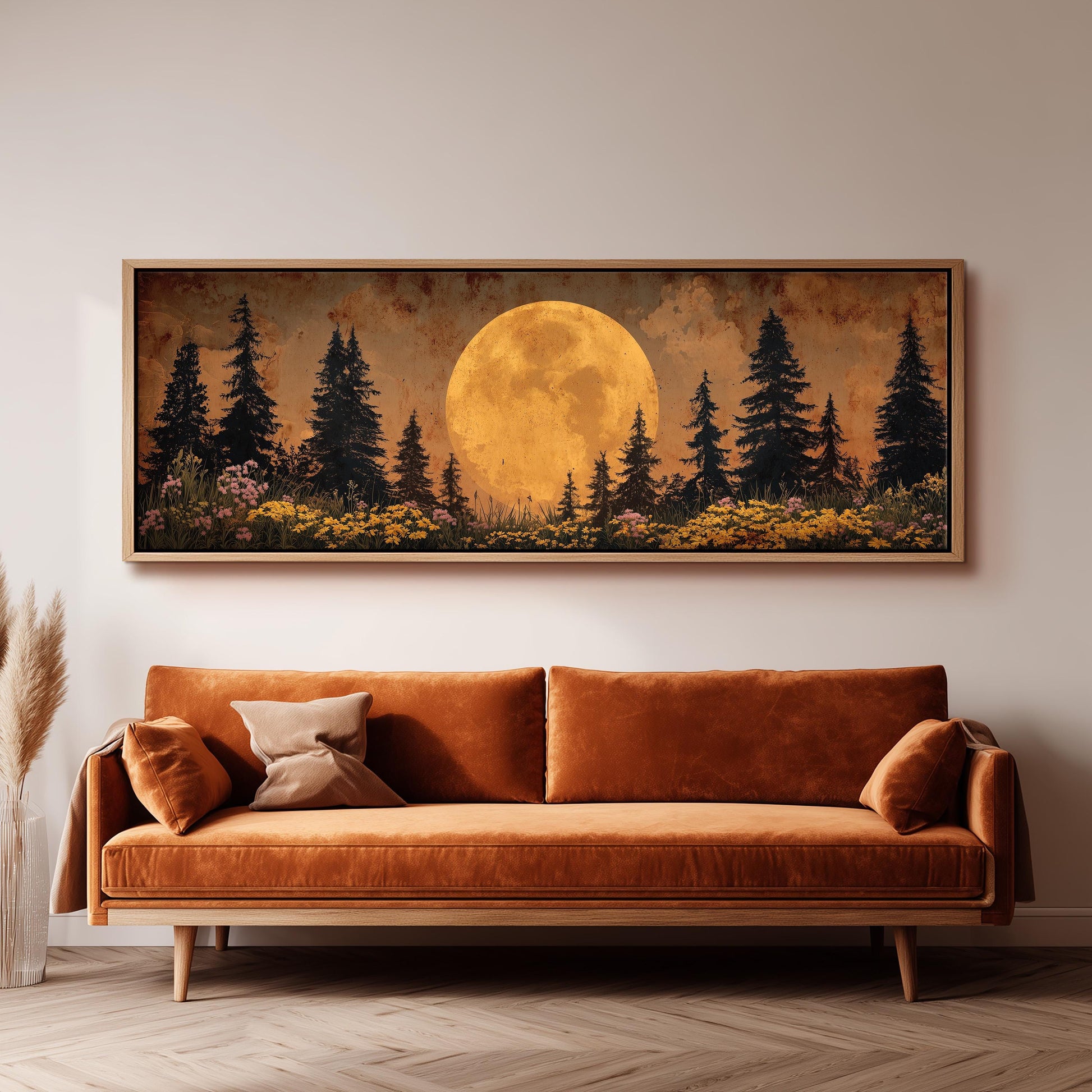 a large, framed painting of a serene landscape with a full moon, pine trees, and a field of flowers. The painting is hanging on a wall above a brown sofa, creating a cozy and inviting atmosphere in the room.