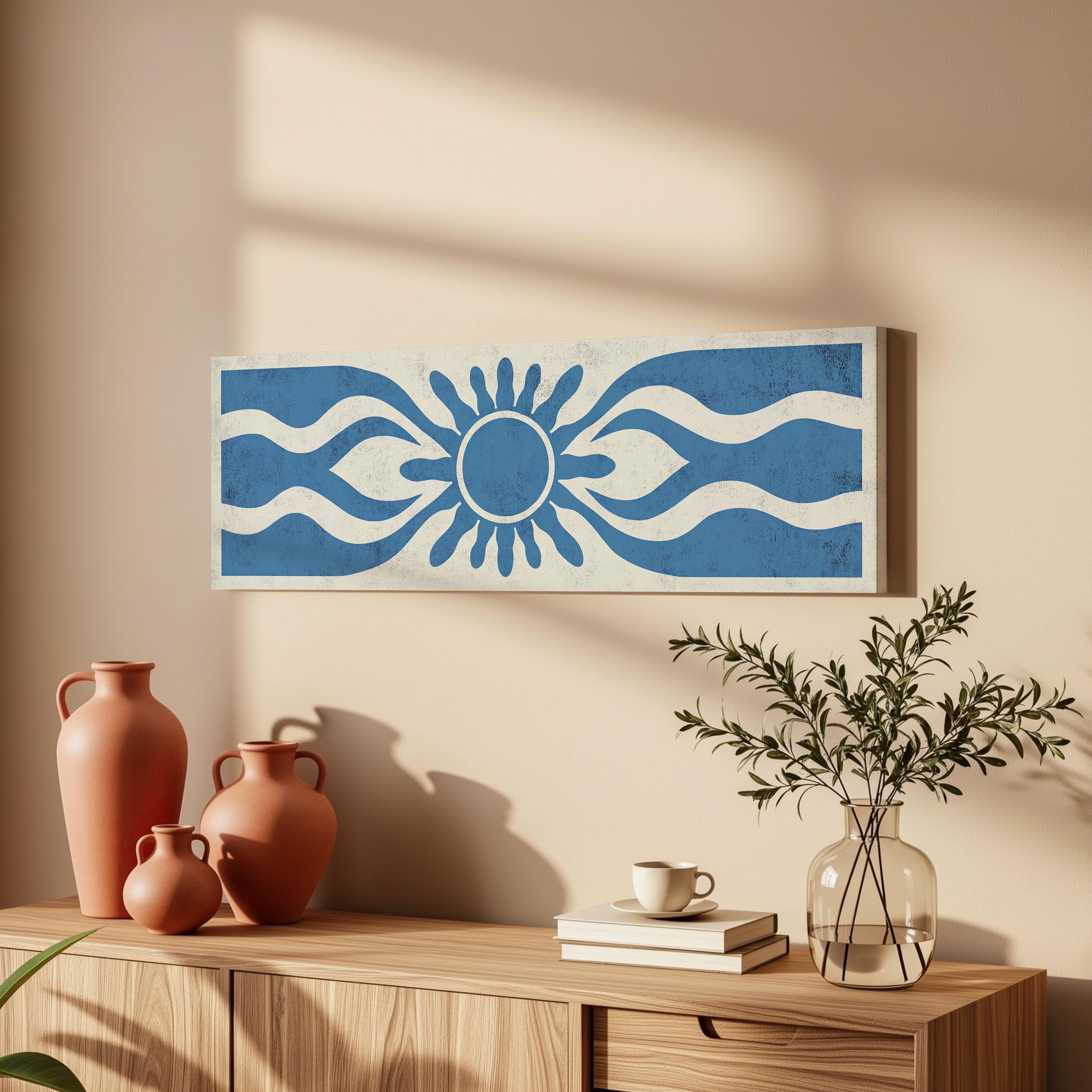 a wooden cabinet with a vase of greenery, a coffee cup, and a stack of books on top. Above the cabinet, there is a framed artwork depicting a blue and white sun design.