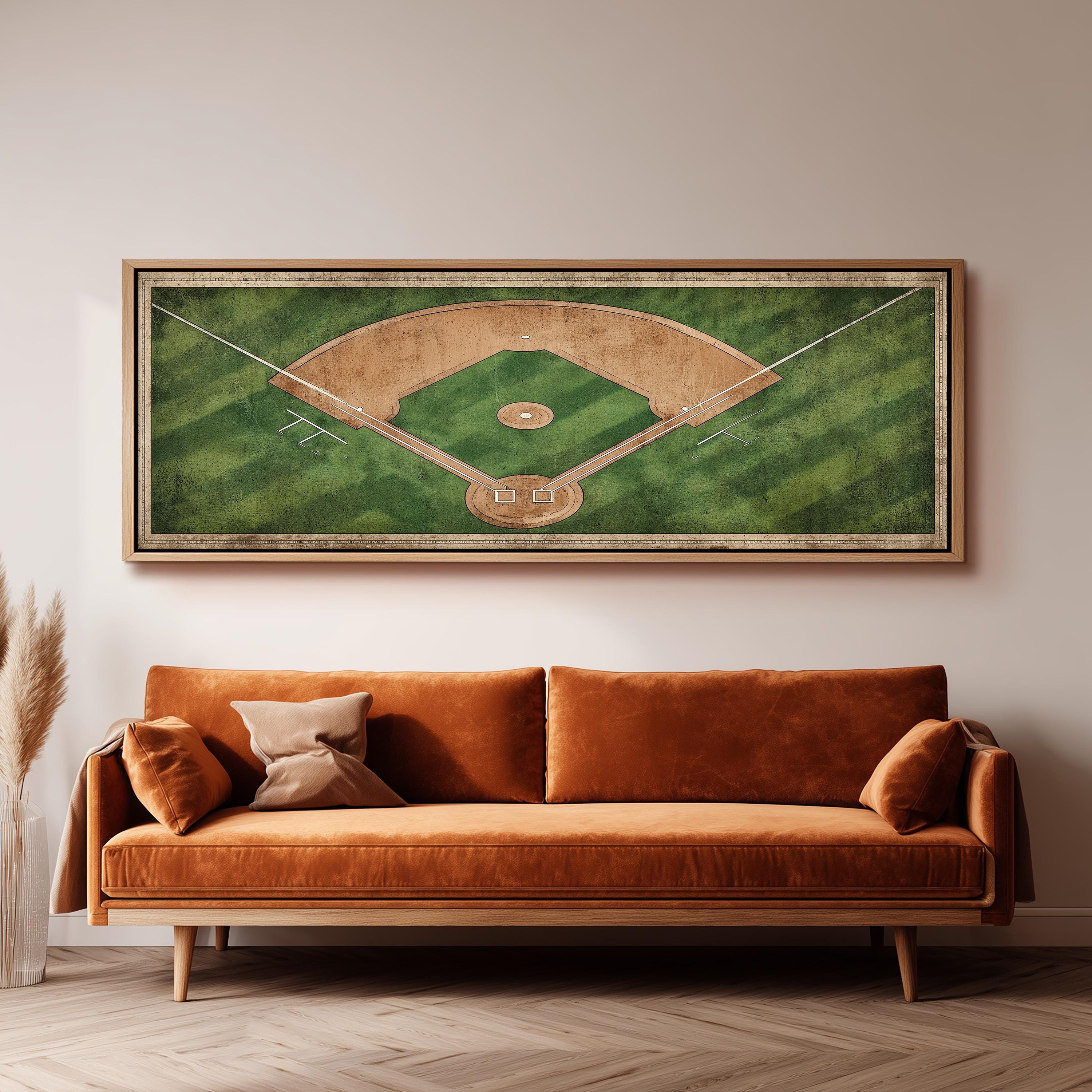 a large framed picture of a baseball field hanging on a wall above a brown sofa.