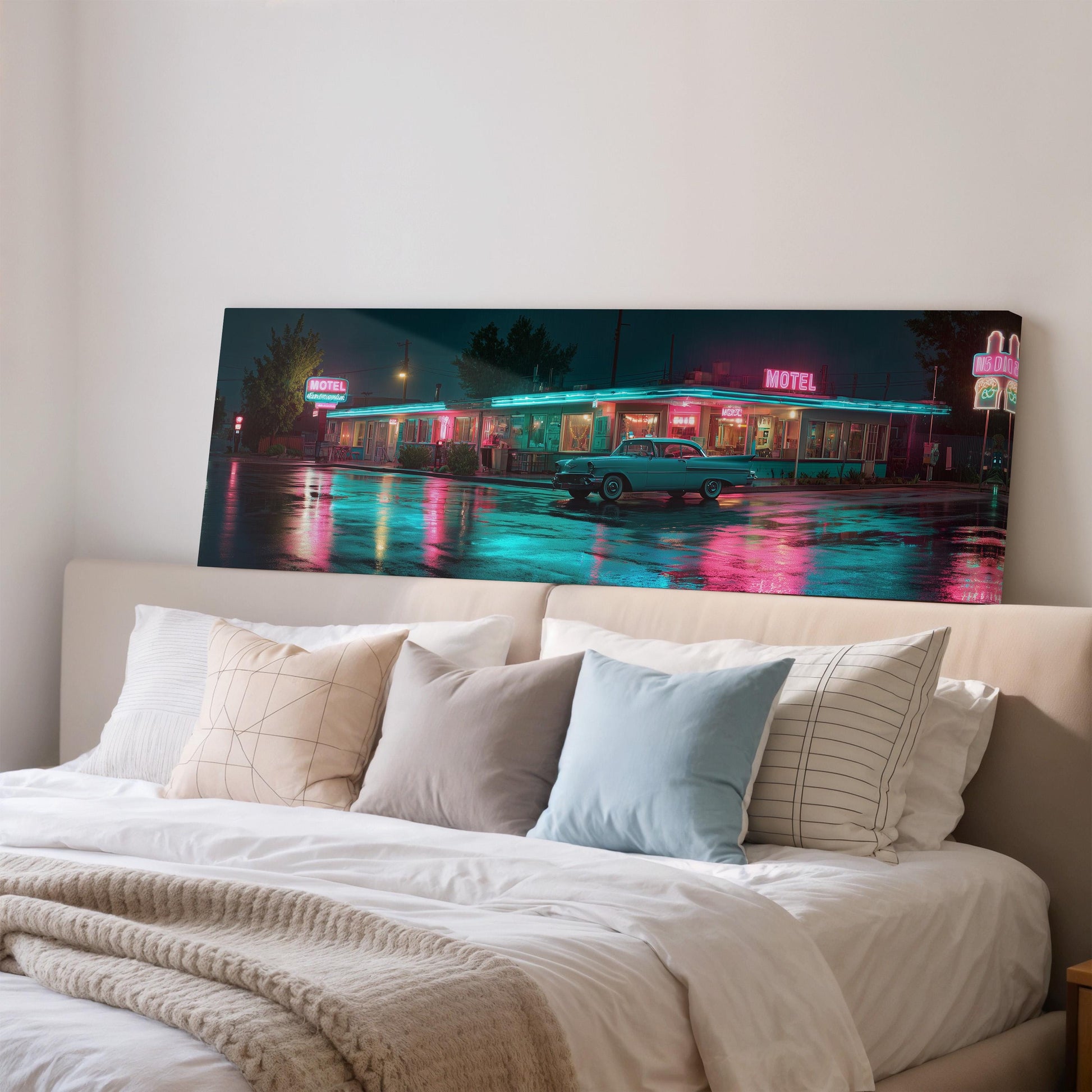 A large, colorful painting of a motel at night is displayed on the wall above a bed with white bedding.