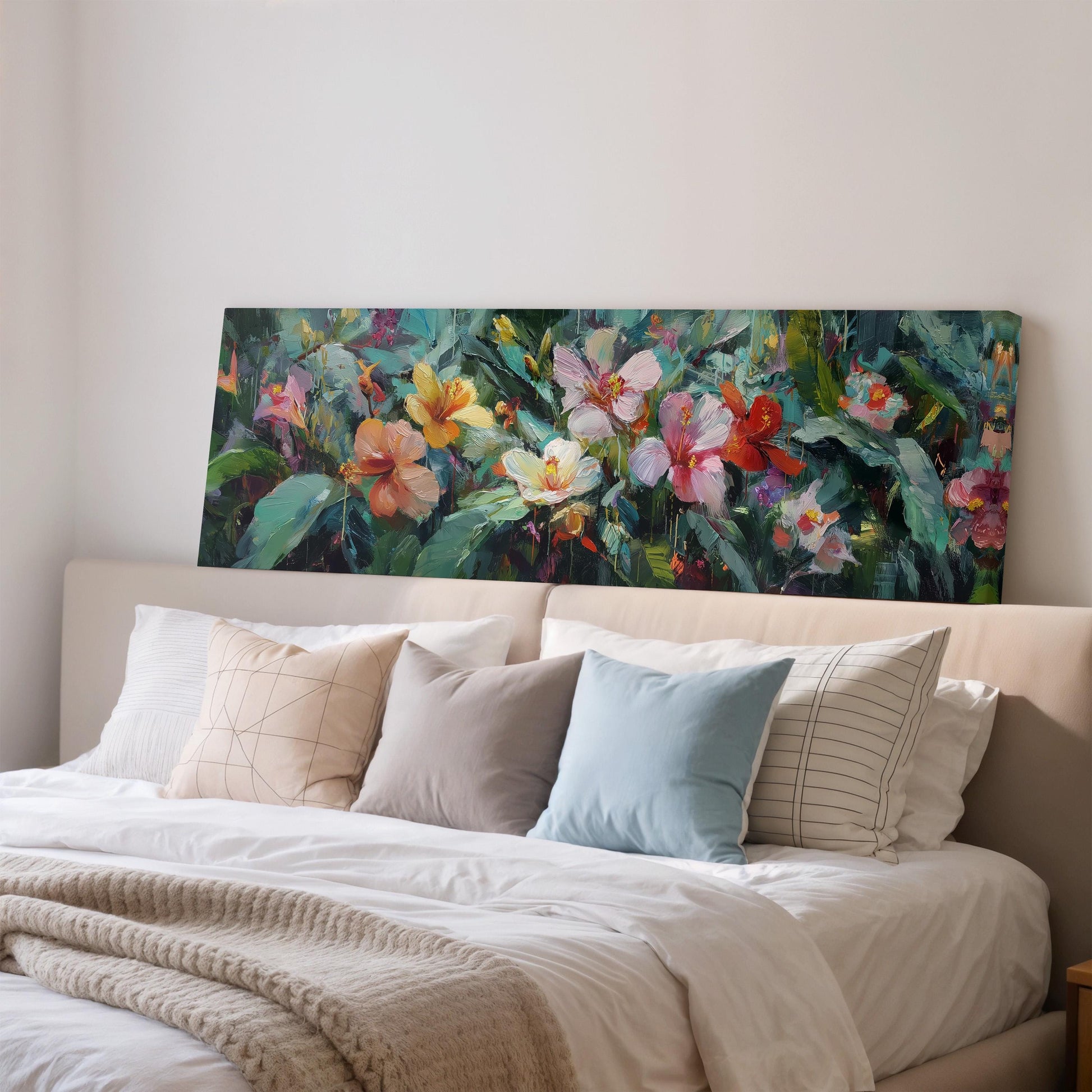 a large, colorful painting of flowers hanging above a bed with white pillows and a gray blanket.