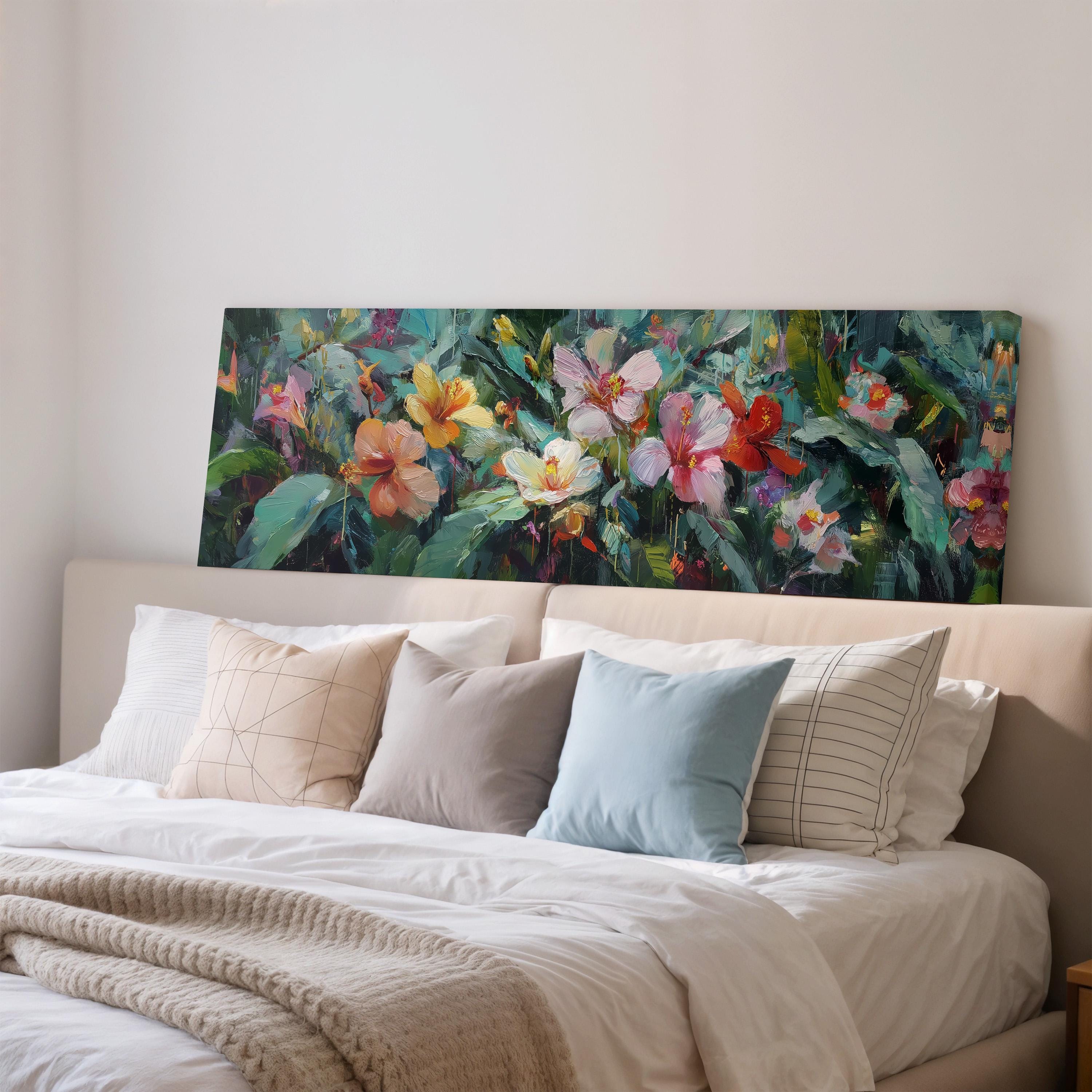 a large, colorful painting of flowers hanging above a bed with white pillows and a gray blanket.