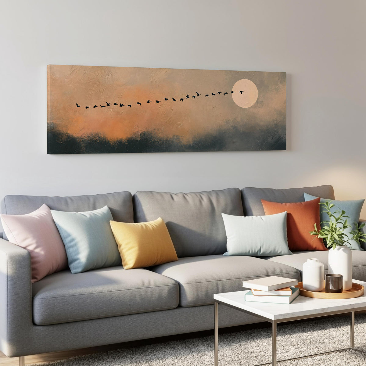 Migrating birds passing a moon at peach dusk panoramic canvas print above a grey sofa in a living room