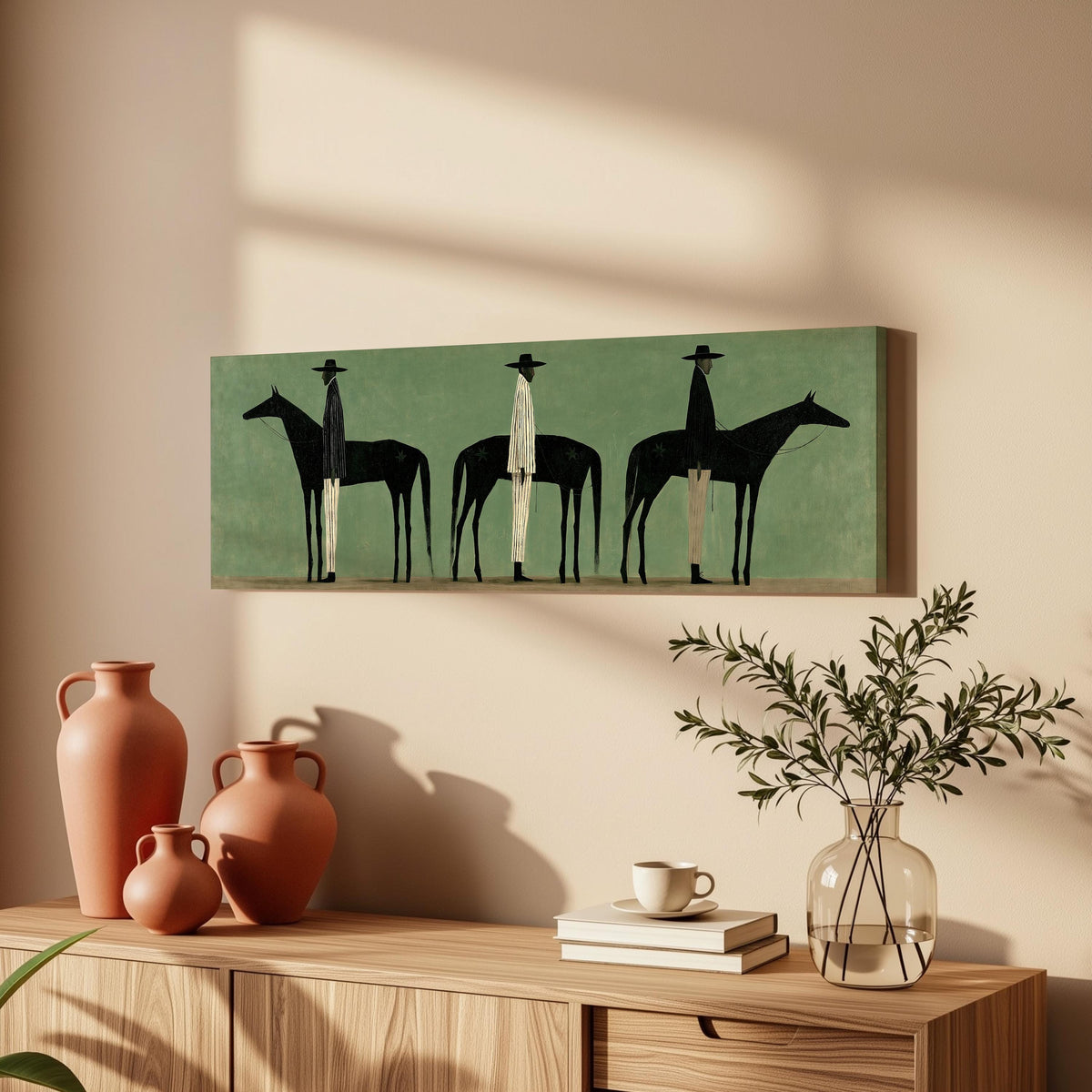 Three stylized cowboys with horses on sage green long horizontal canvas print above a wooden sideboard