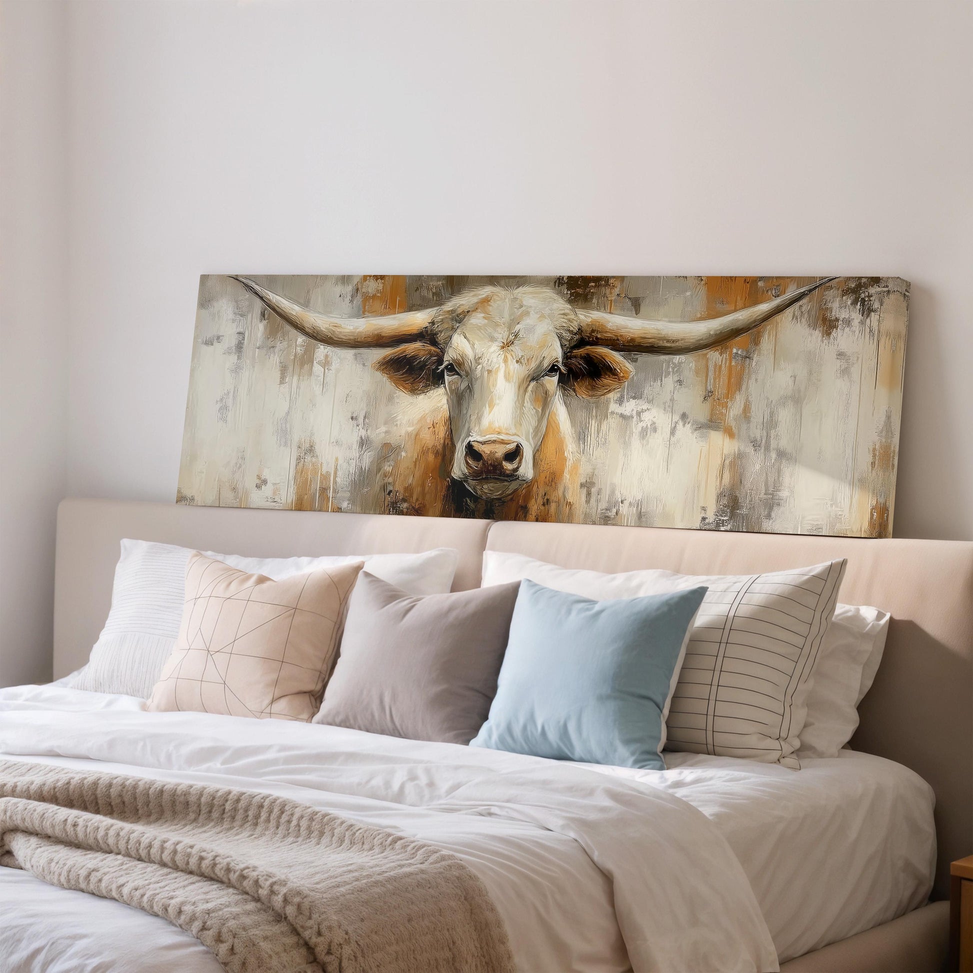 a large painting of a bull's head on a wall above a bed with white bedding and pillows.