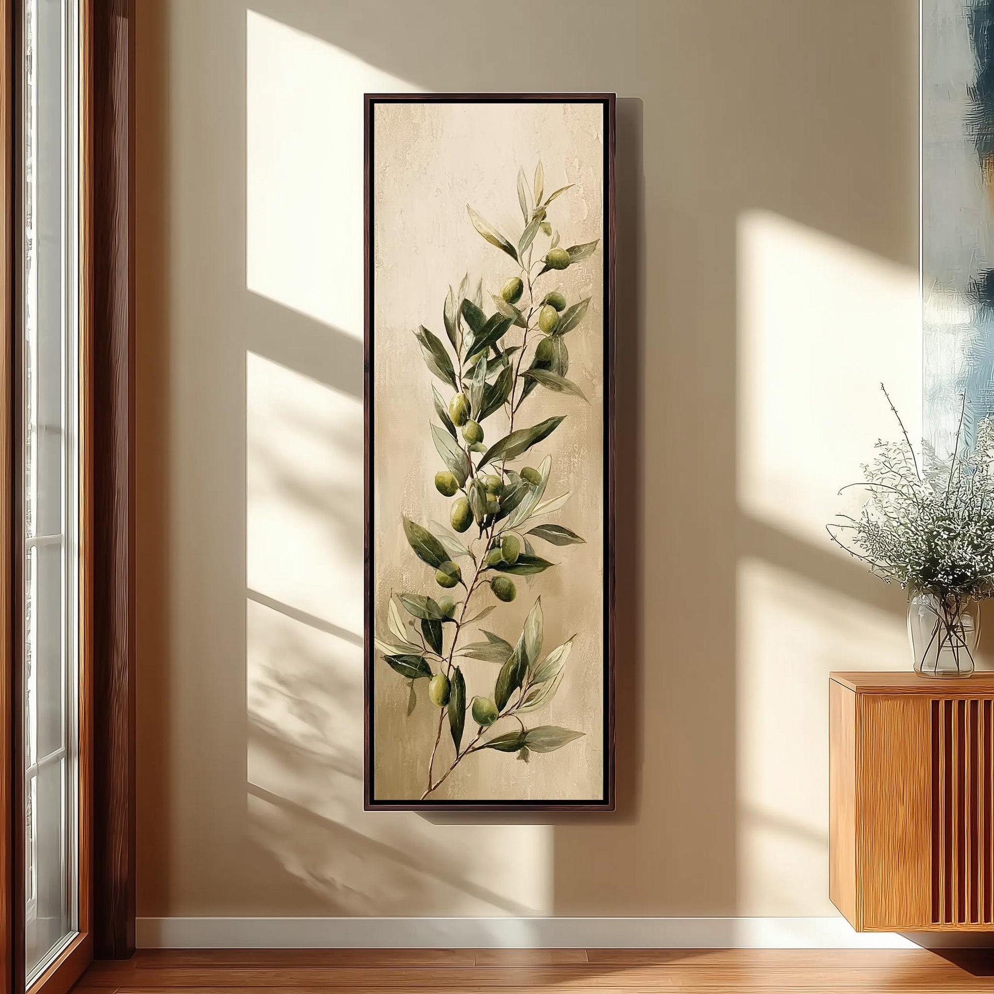 a large framed painting of a green olive branch with green olives hanging on a wall in a room with a wooden cabinet and a vase of flowers.