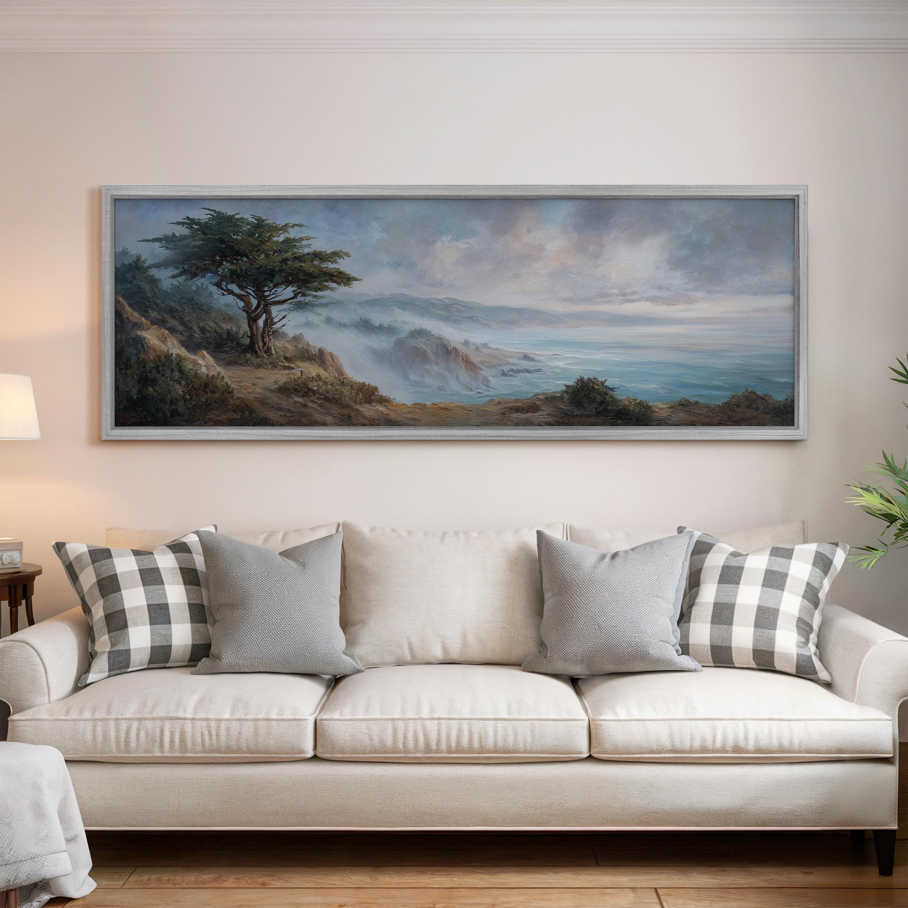a large painting of a landscape hanging on a wall above a white sofa with gray and white patterned pillows.