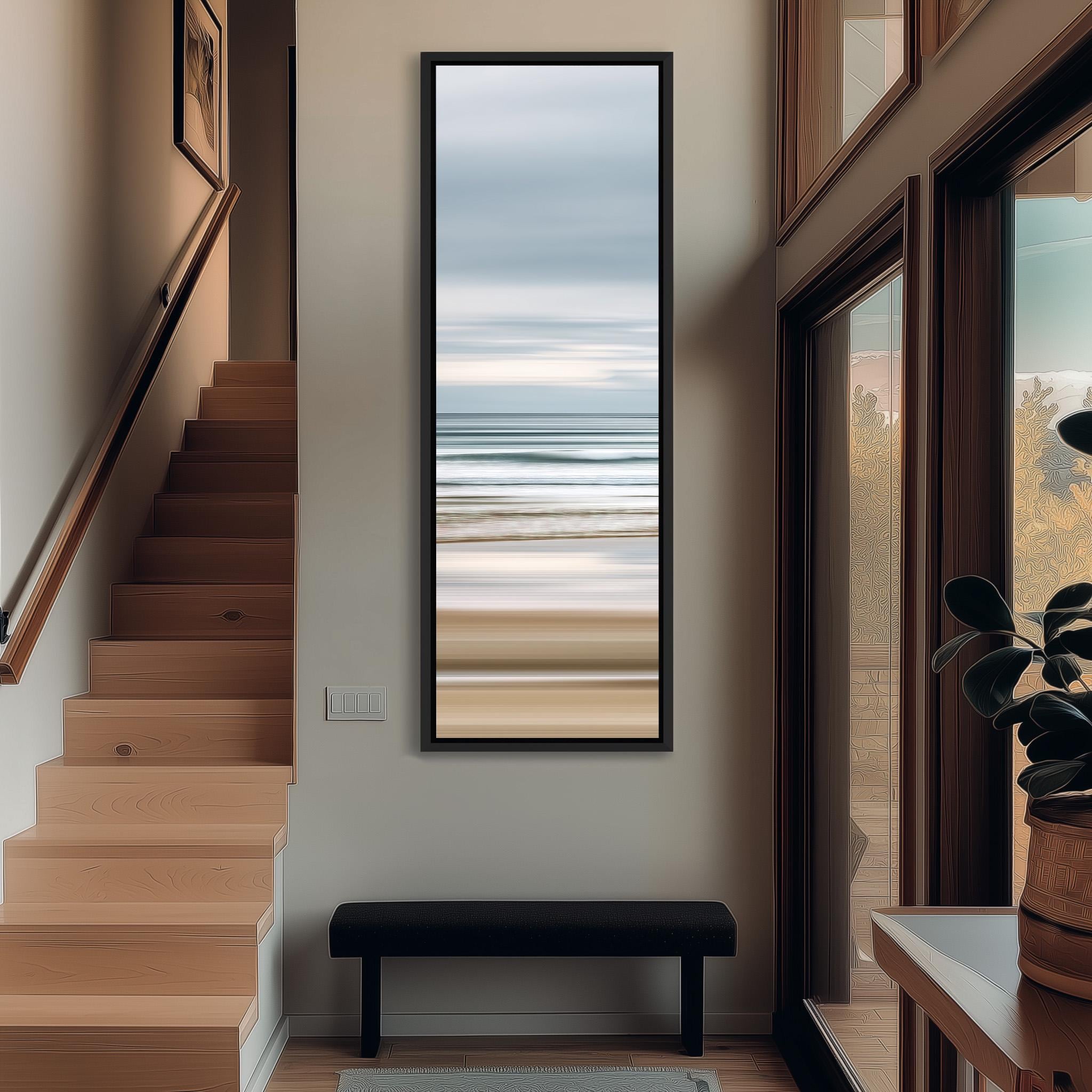 a hallway with a large window that provides a view of the ocean. The window is framed with a black border and has a painting of the ocean hanging on the wall above it. The hallway has a wooden staircase leading up to the second floor, and there is a bench in the foreground.