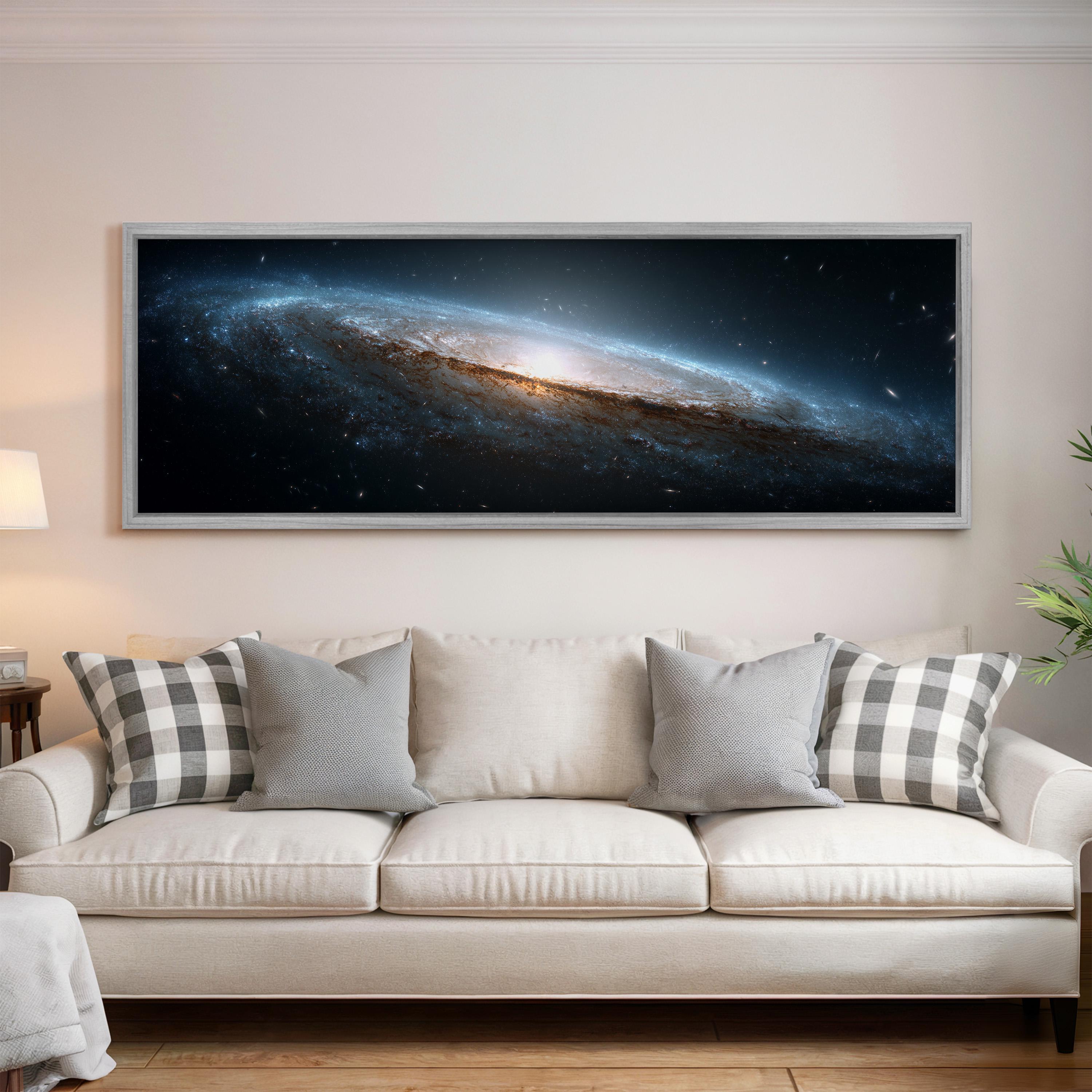 a large, framed artwork depicting a spiral galaxy hanging on a wall above a white couch with gray and white plaid throw pillows.