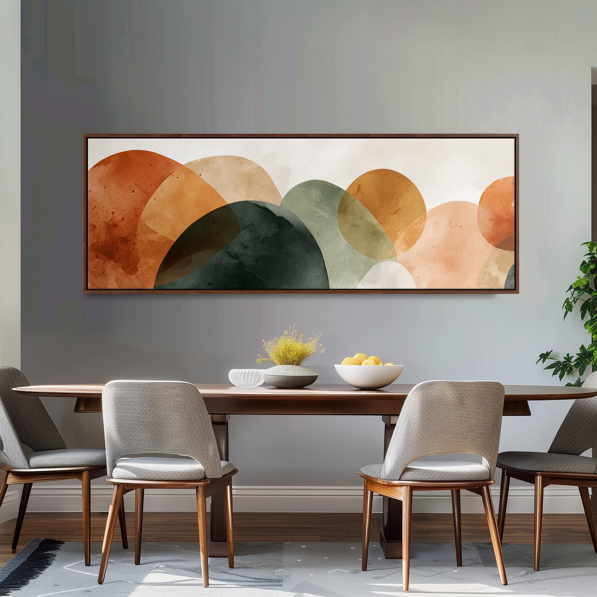 a modern dining room with a wooden table and four chairs. Above the table, there is a large abstract painting with various shades of orange, green, and brown circles. The painting is hung on a gray wall, creating a cohesive and stylish atmosphere in the room.