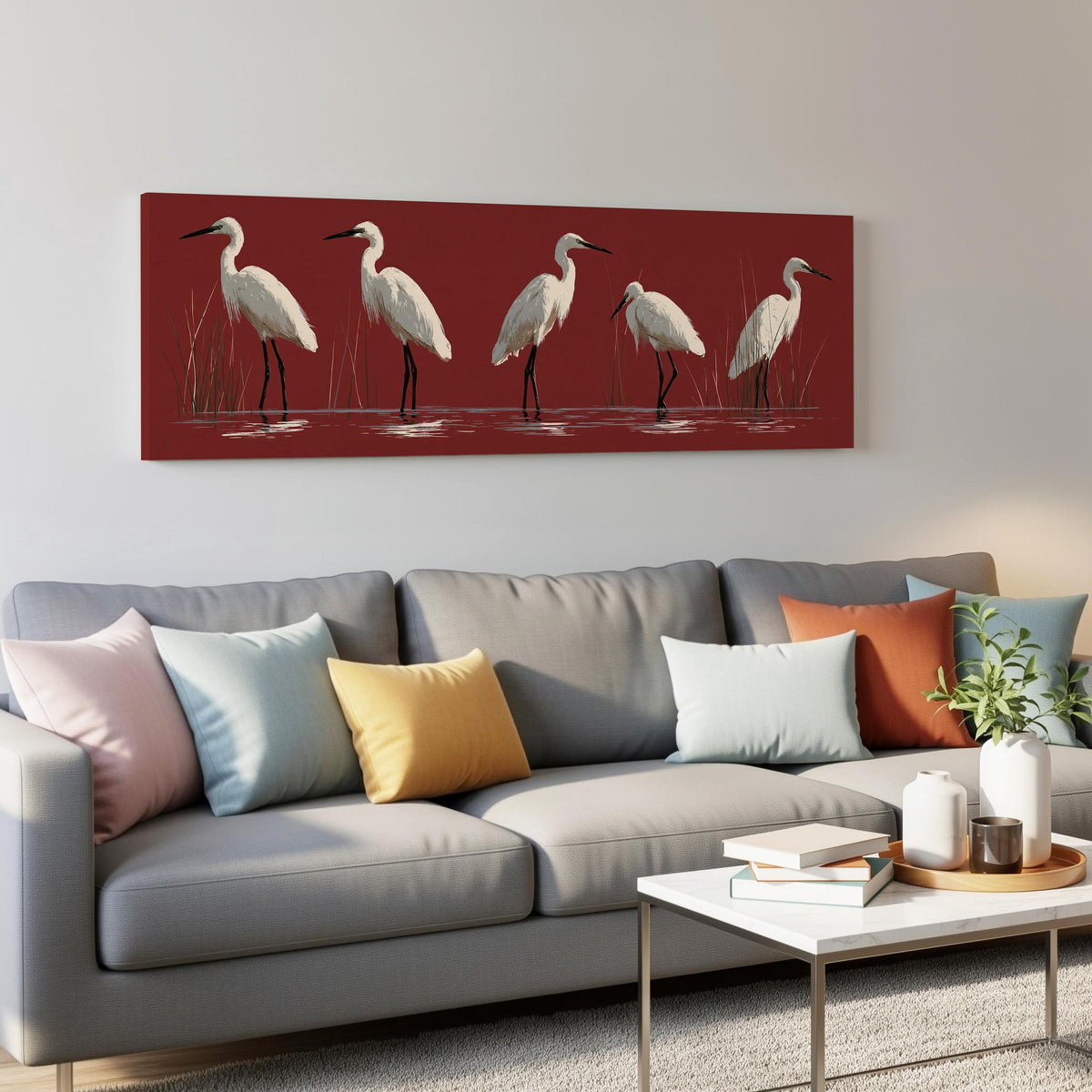 White egrets wading on crimson red panoramic canvas print above a grey sofa in a living room
