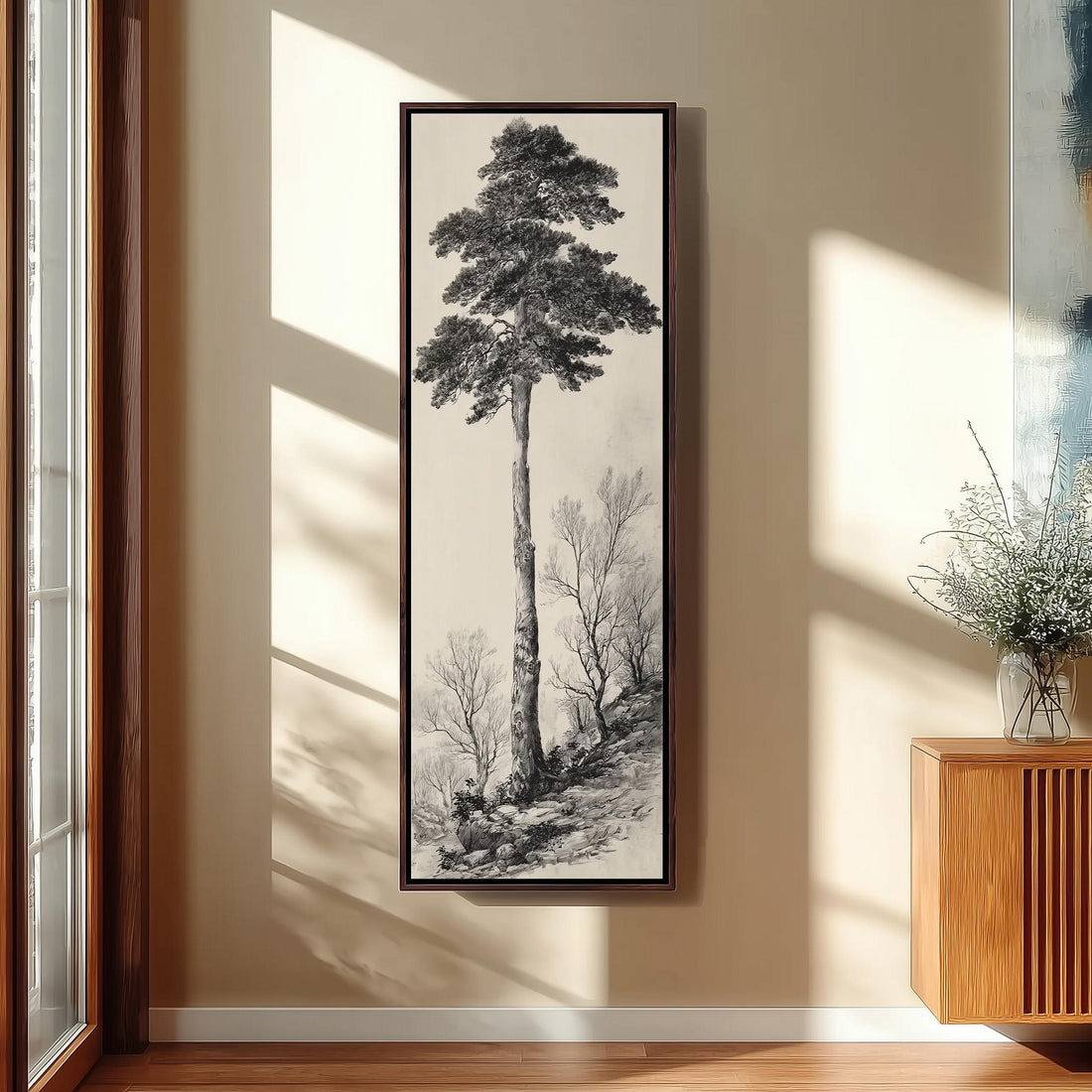 a large black and white painting of a tall tree hanging on a wall in a room with wooden furniture.