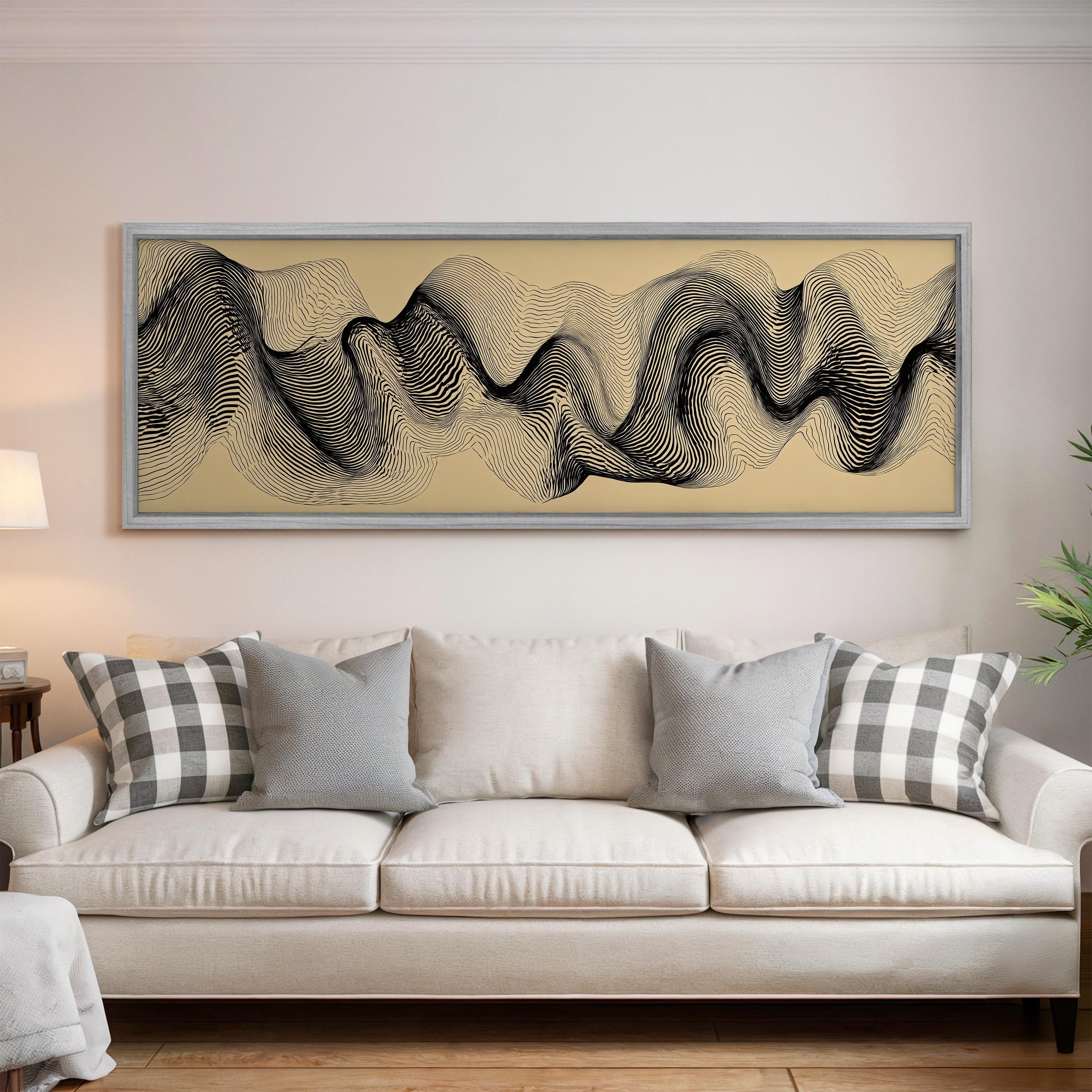 a large abstract painting hanging on a wall above a white sofa with gray and white patterned pillows.