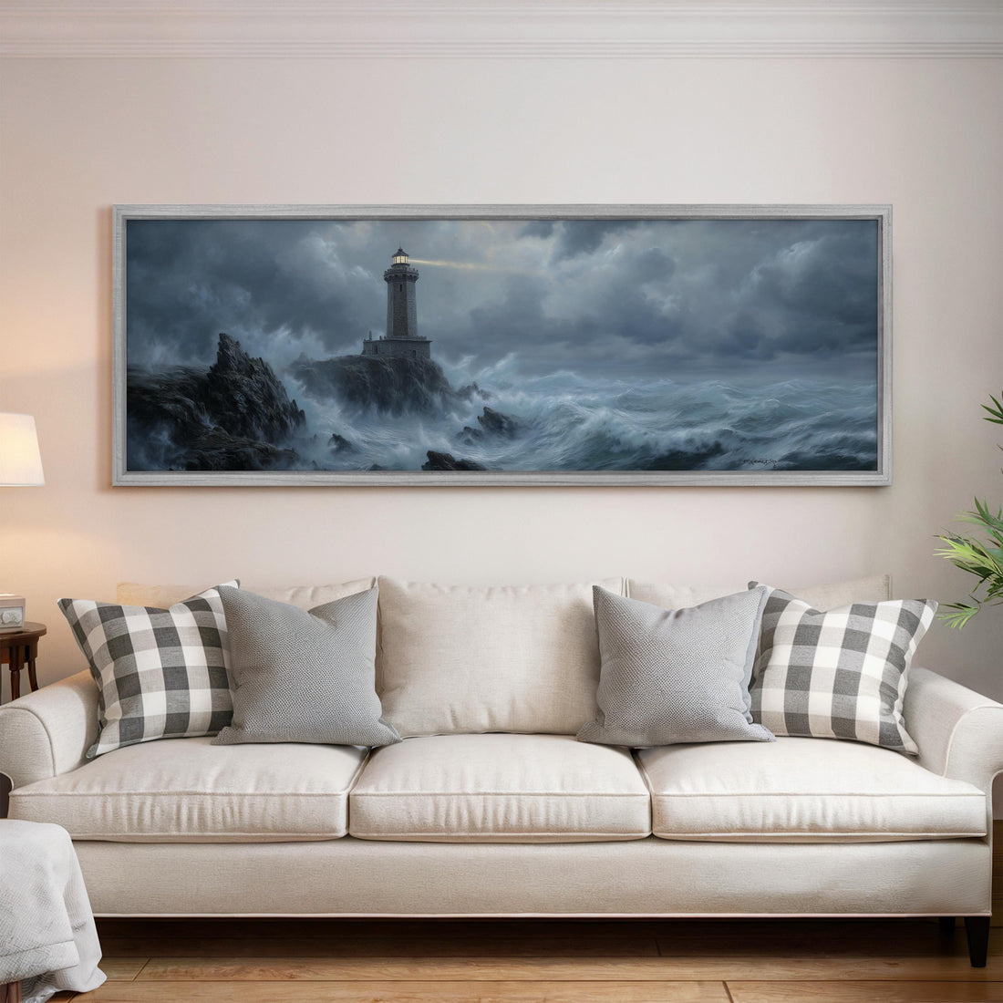 a large painting of a lighthouse on a stormy sea hanging on a wall above a white sofa with patterned throw pillows.