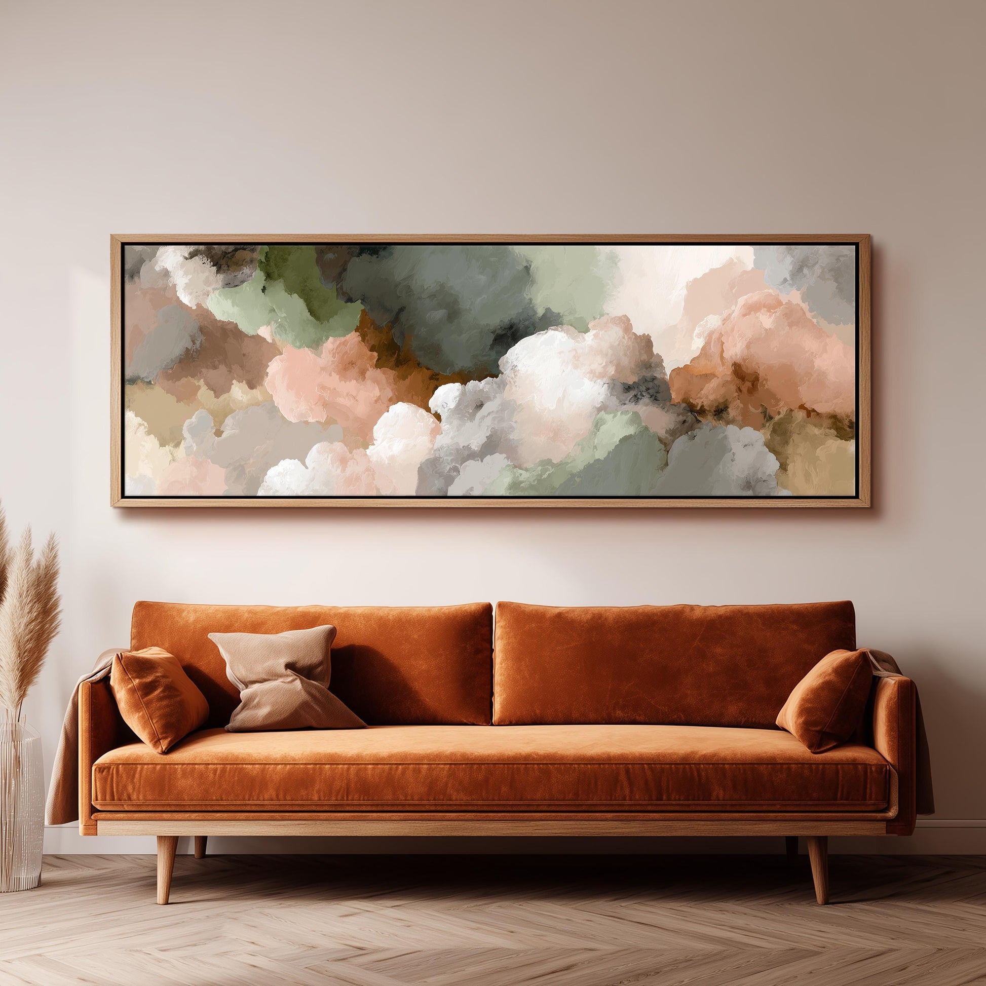 a large, framed painting of clouds hanging on a wall above a brown sofa with orange cushions.