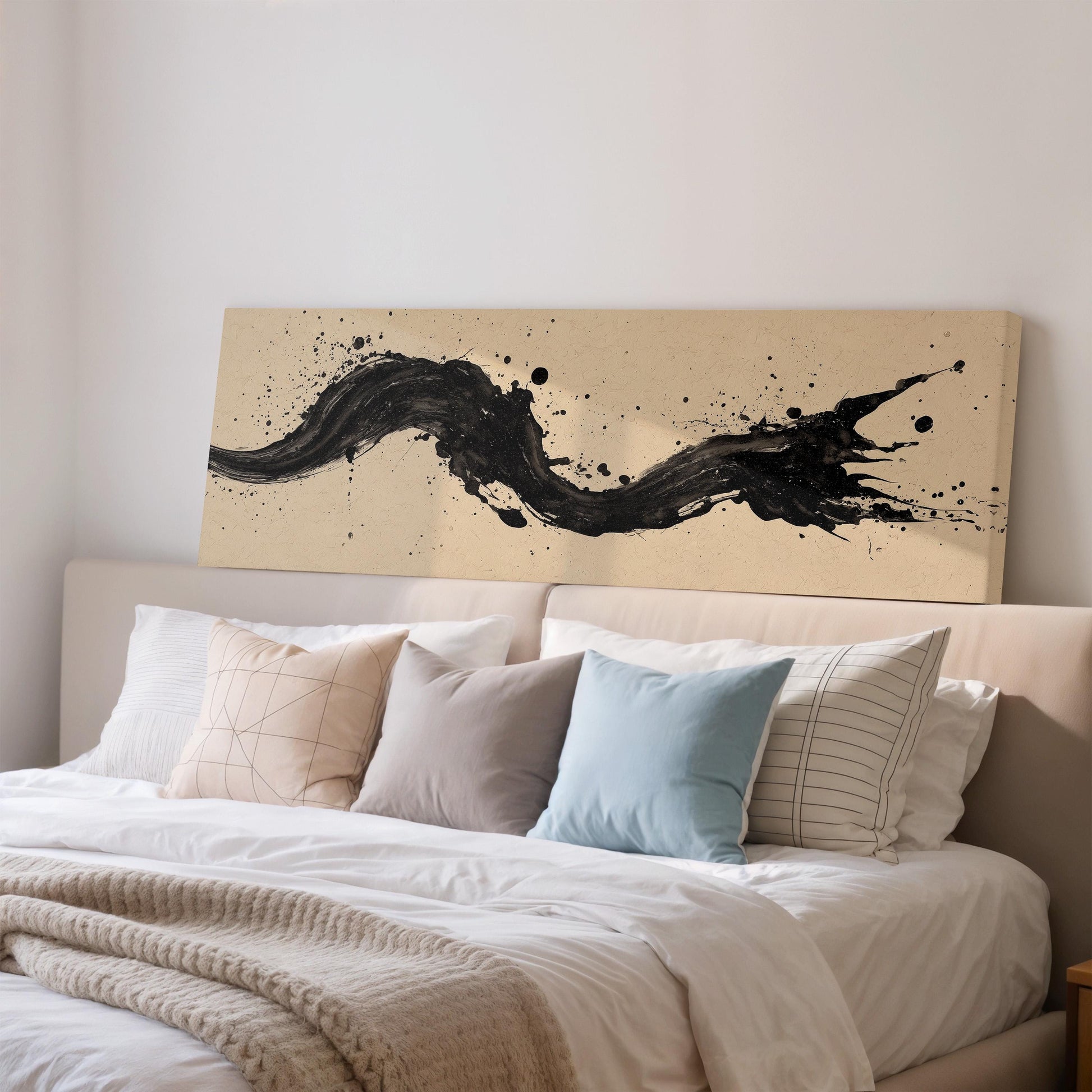 a bedroom with a large bed covered in white sheets and pillows. Above the bed, there is a large canvas print featuring a black abstract design with splashes of color.