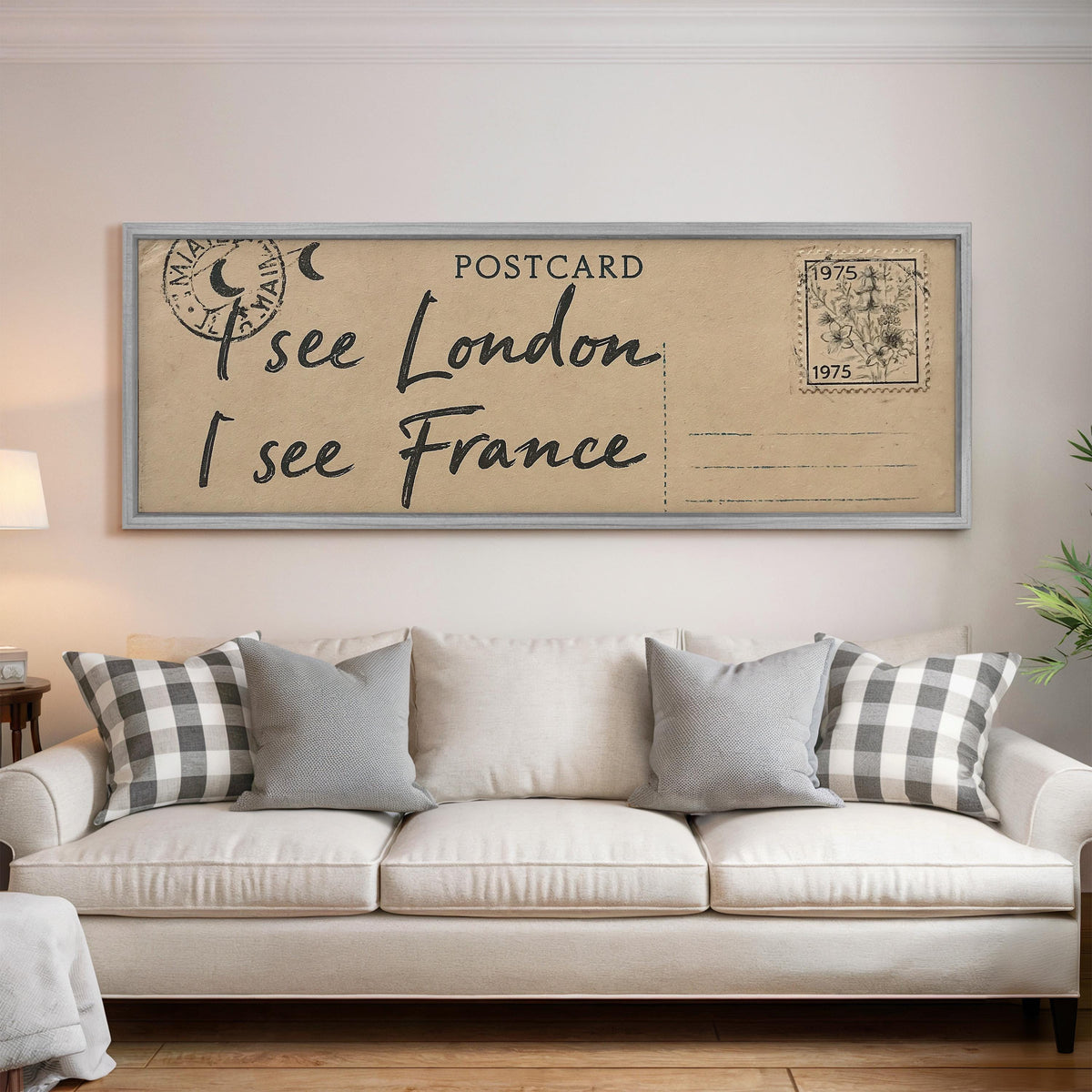 Postcard saying I see London, I see France panoramic canvas print above a white sofa in a bright living room