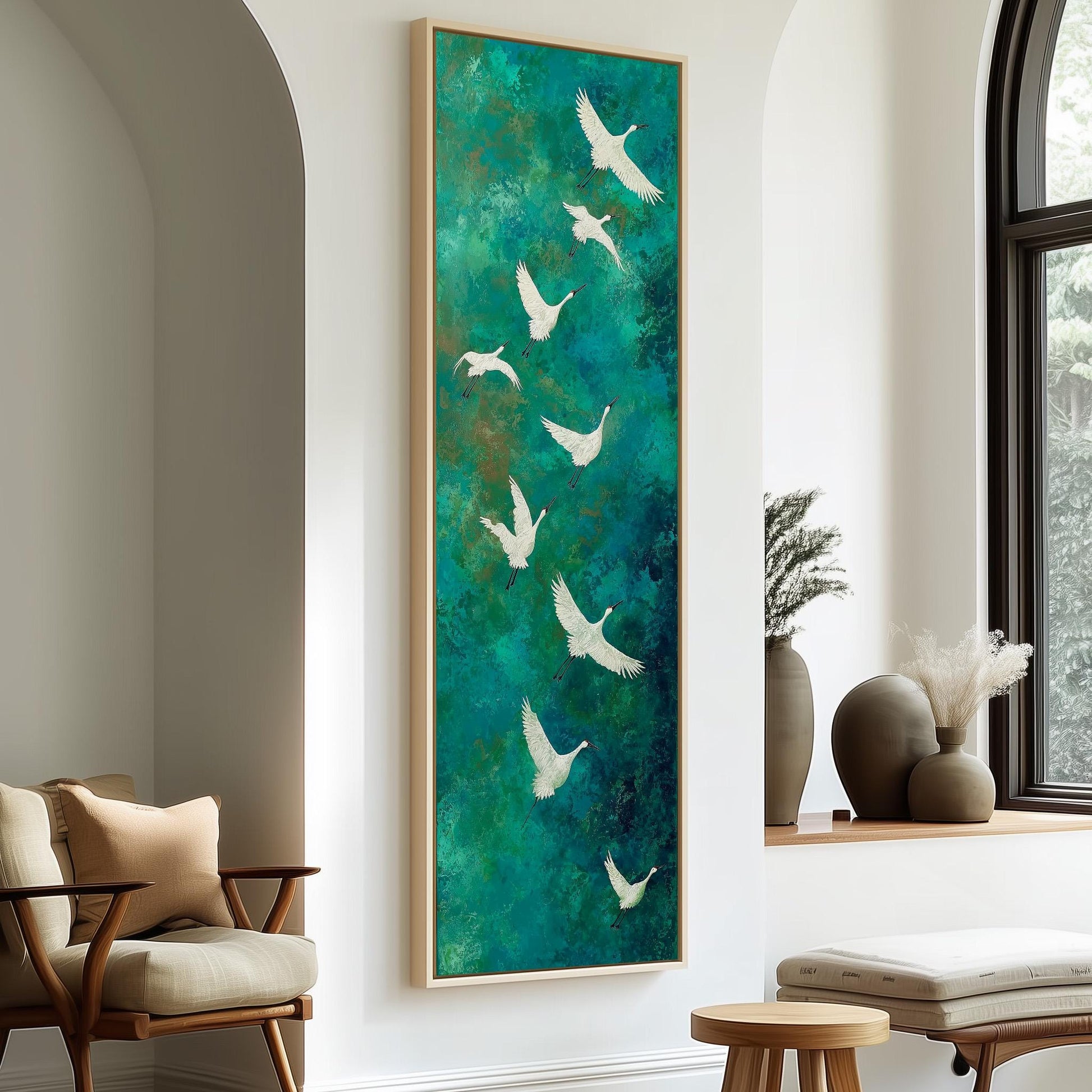 a large painting of white birds against a green background, hanging on a wall in a room with a wooden chair and a small table.